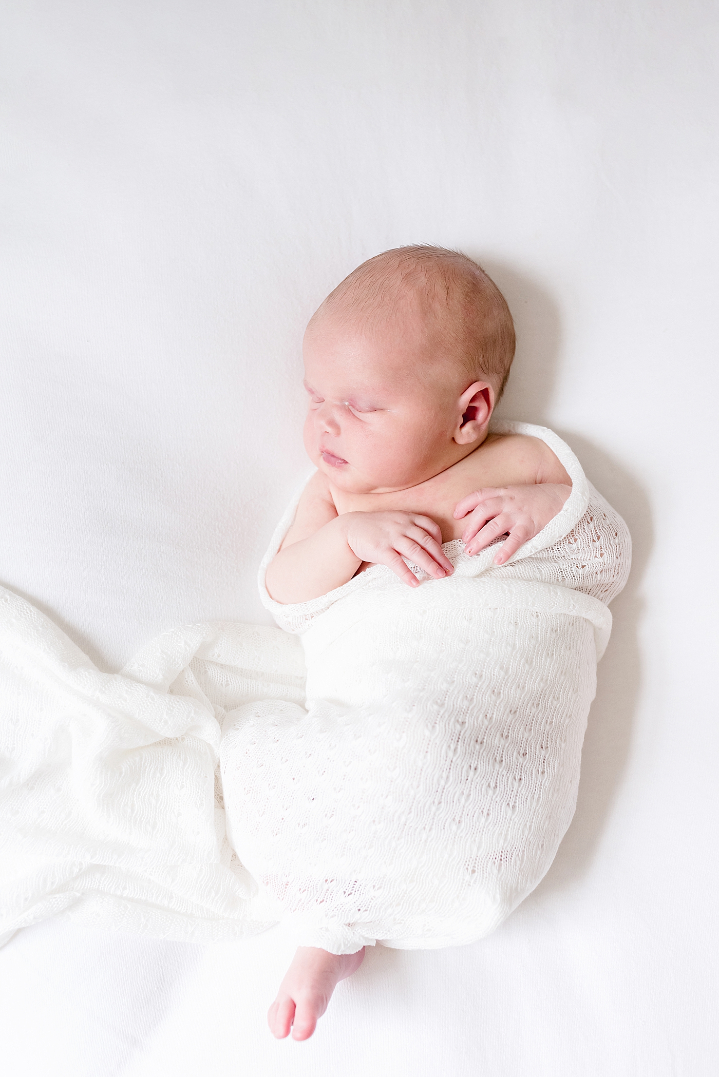 Newborn baby girl wrapped in a swaddle | Photo by Anna Wisjo Photography