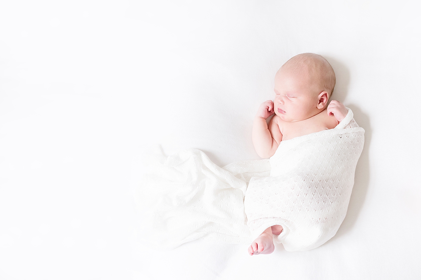 Newborn baby in white swaddle | Photo by Anna Wisjo Photography