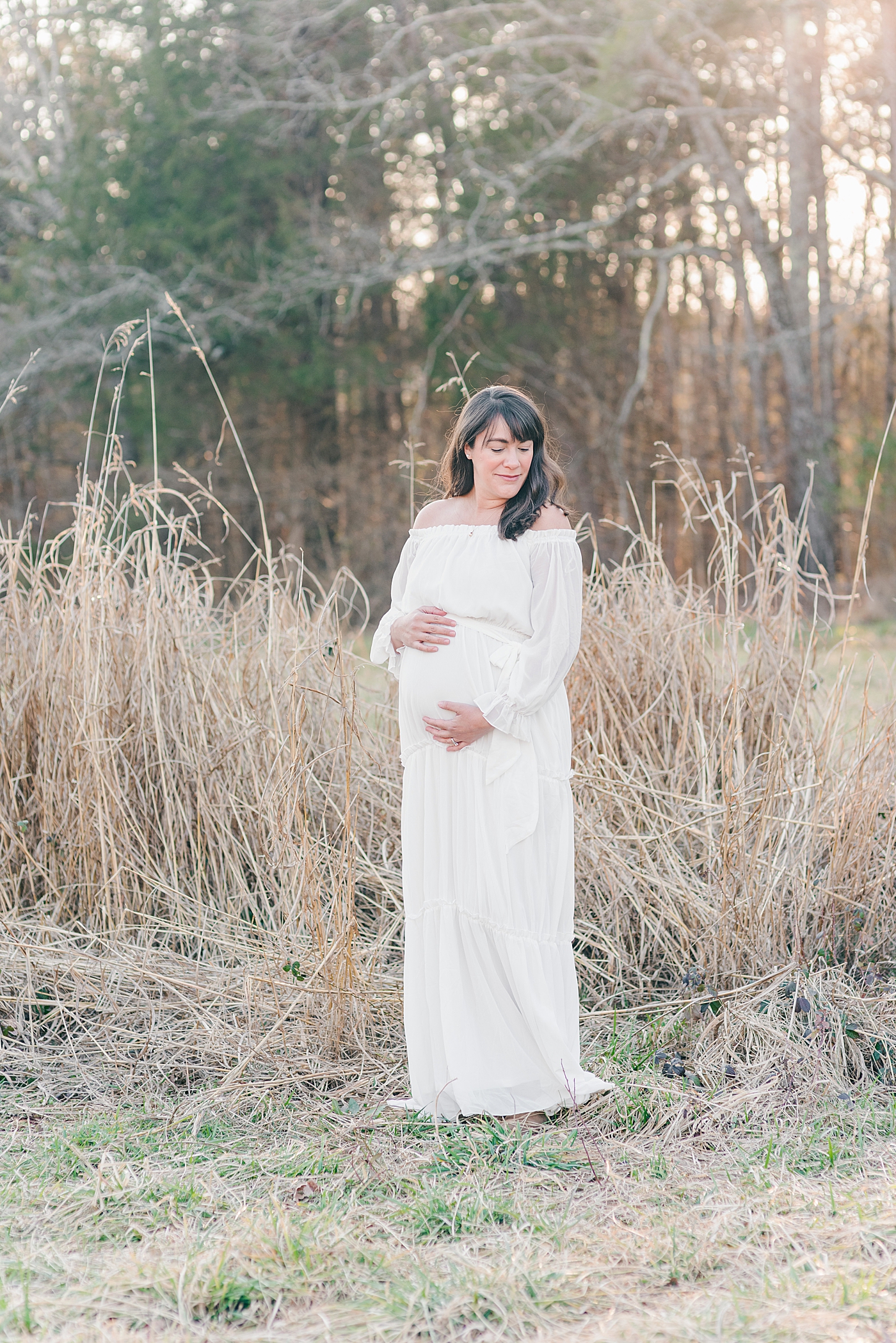 Expecting mom in long white dress in a field during Davidson maternity session | Photo by Anna Wisjo Photography
