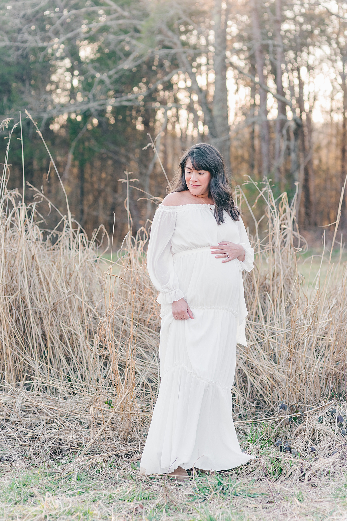 Expecting mom in white dress in a field at sunset | Photo by Anna Wisjo Photography