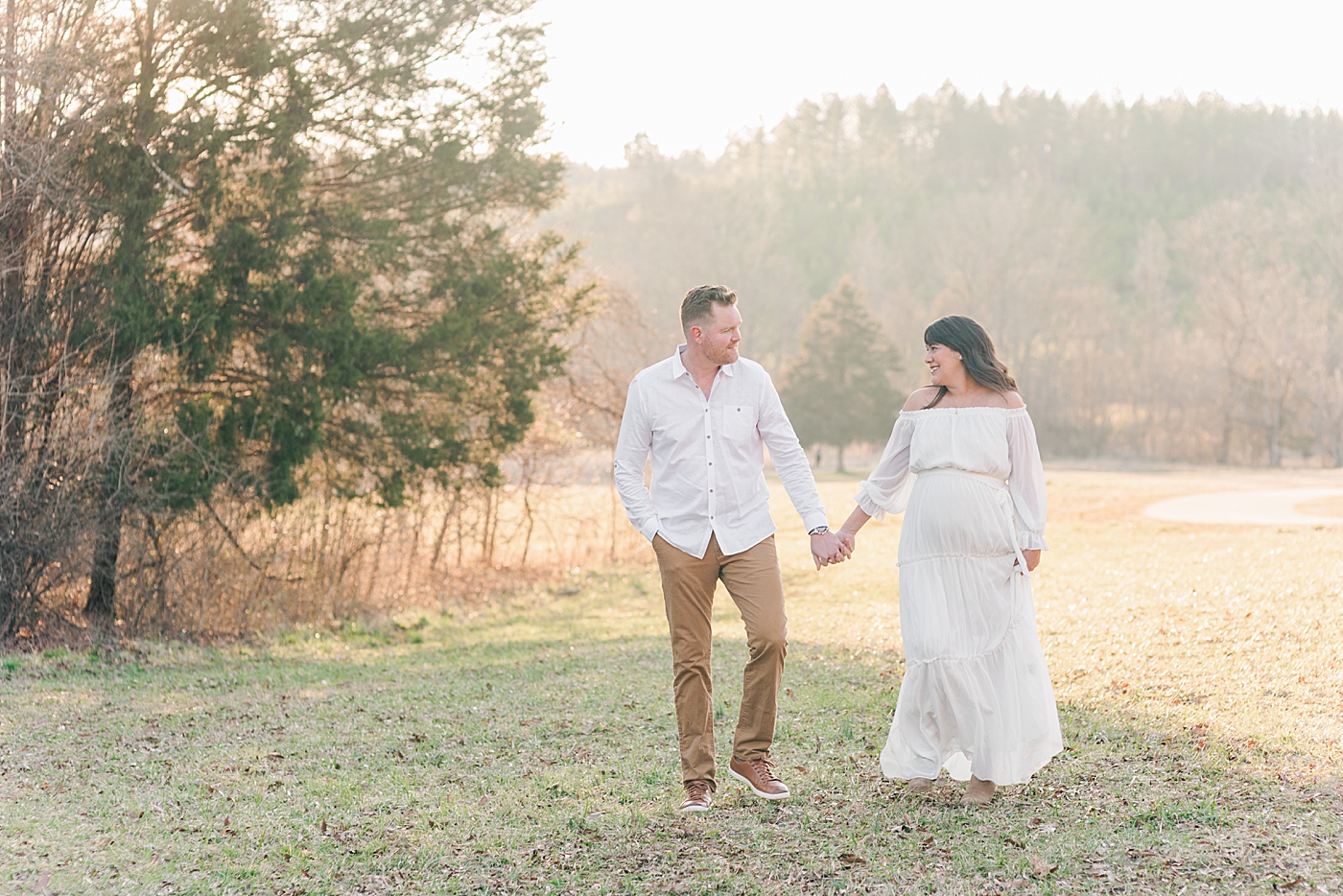 Dad and mom to be walking in a field holding hands for maternity session | Photo by Anna Wisjo Photography