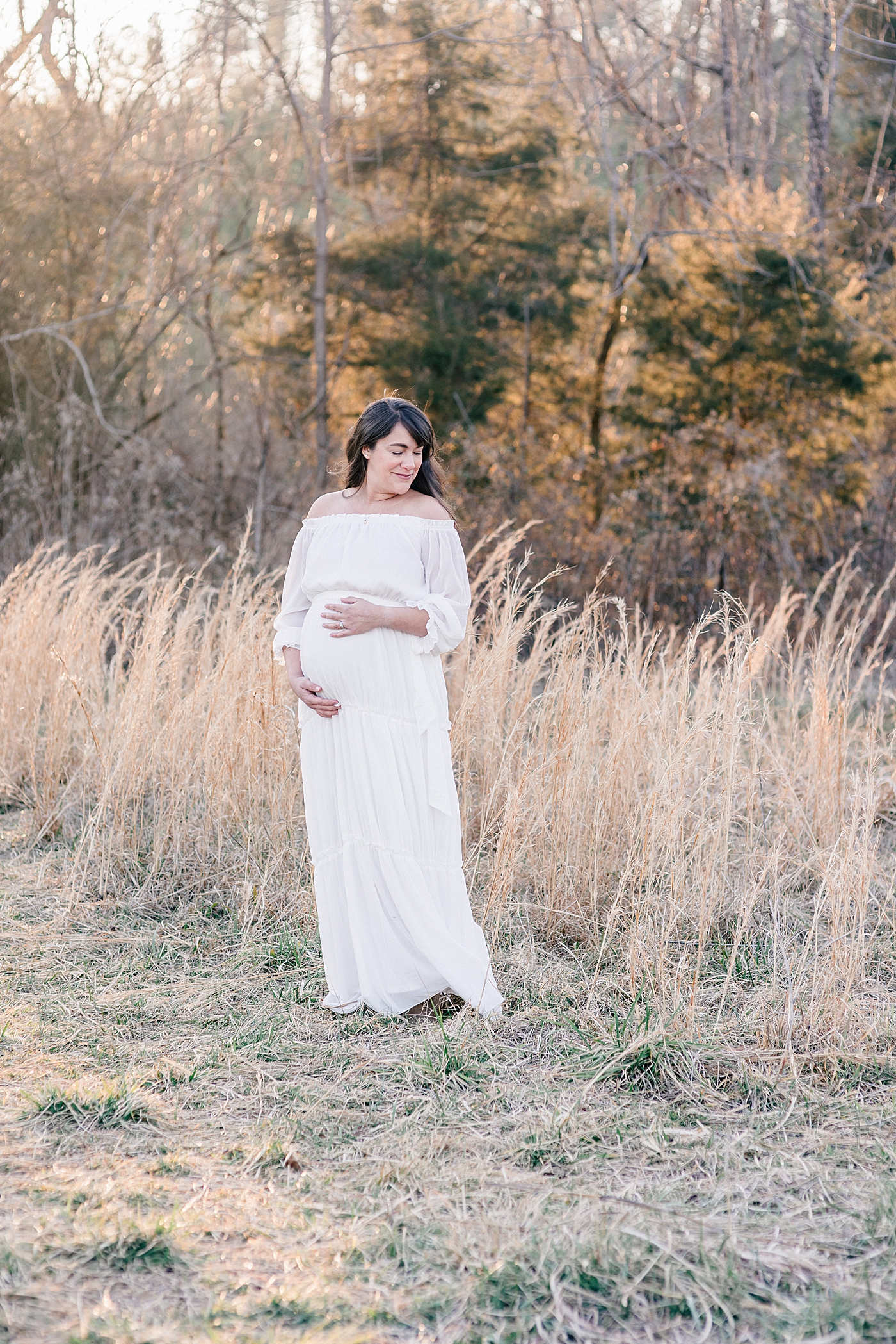 Mother to be in a white dress holding her belly in fisher farm park | Photo by Anna Wisjo Photography