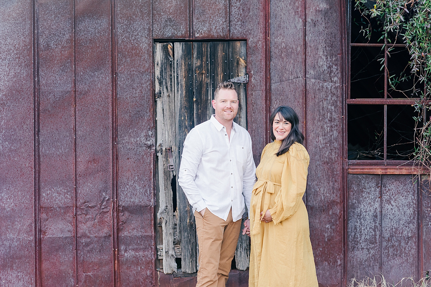 Father and mother to be in front of a red barn | Photo by Anna Wisjo Photography