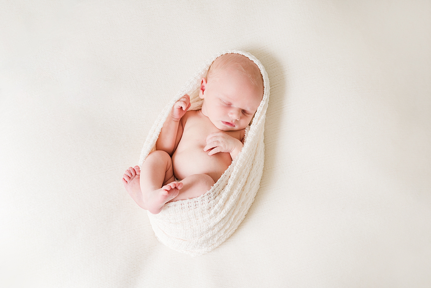 Newborn baby wrapped in soft cream swaddle during Denver NC studio session | Photo by Anna Wisjo Photography