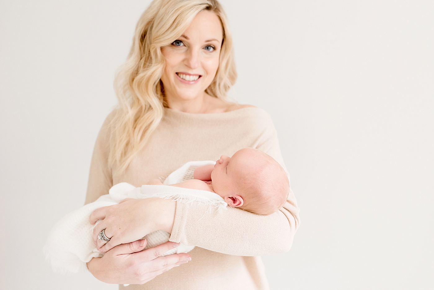 New mom in cream dress holding newborn baby during studio newborn session | Photo by Anna Wisjo Photography