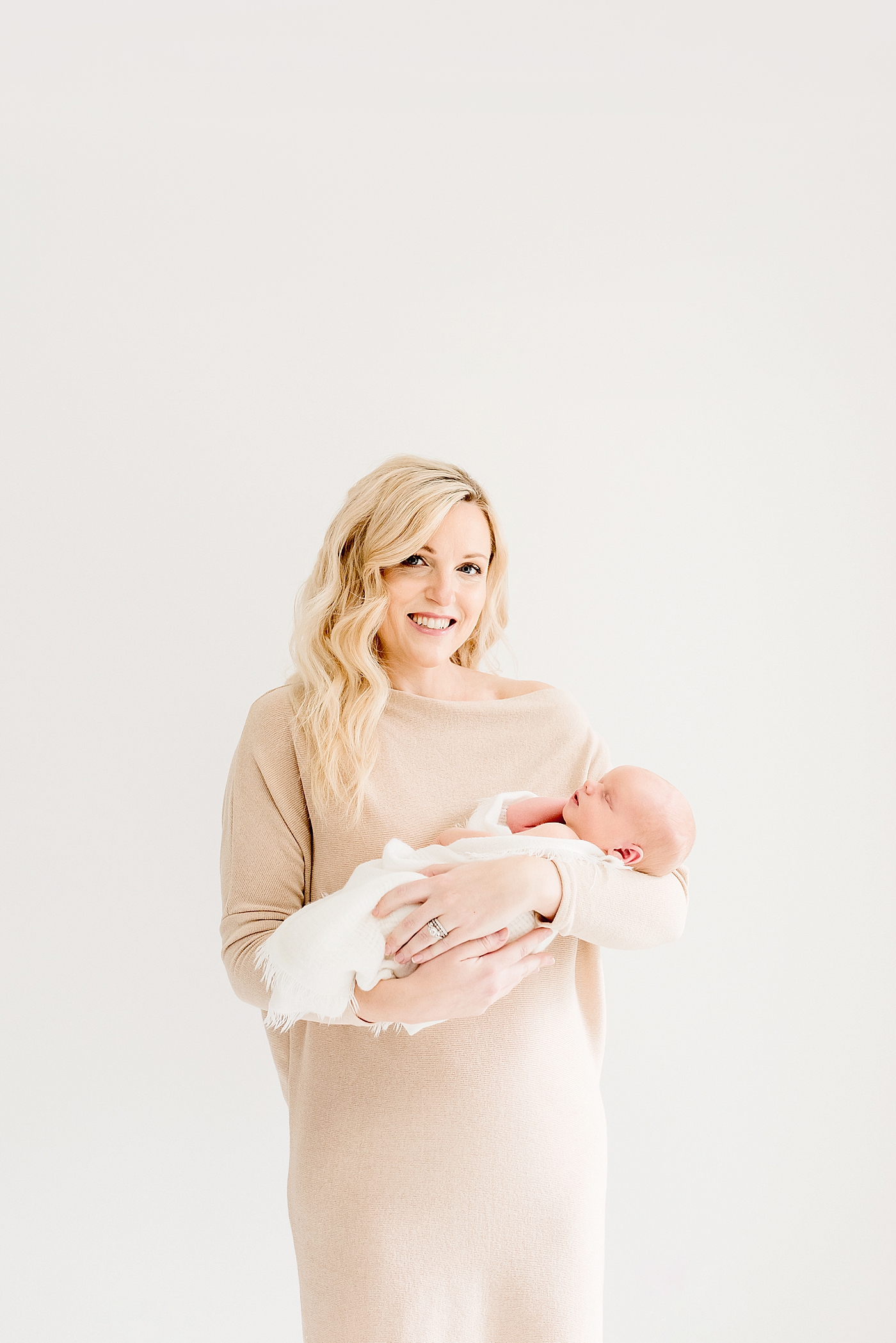 Mom holding newborn baby wrapped in white swaddle | Photo by Anna Wisjo Photography