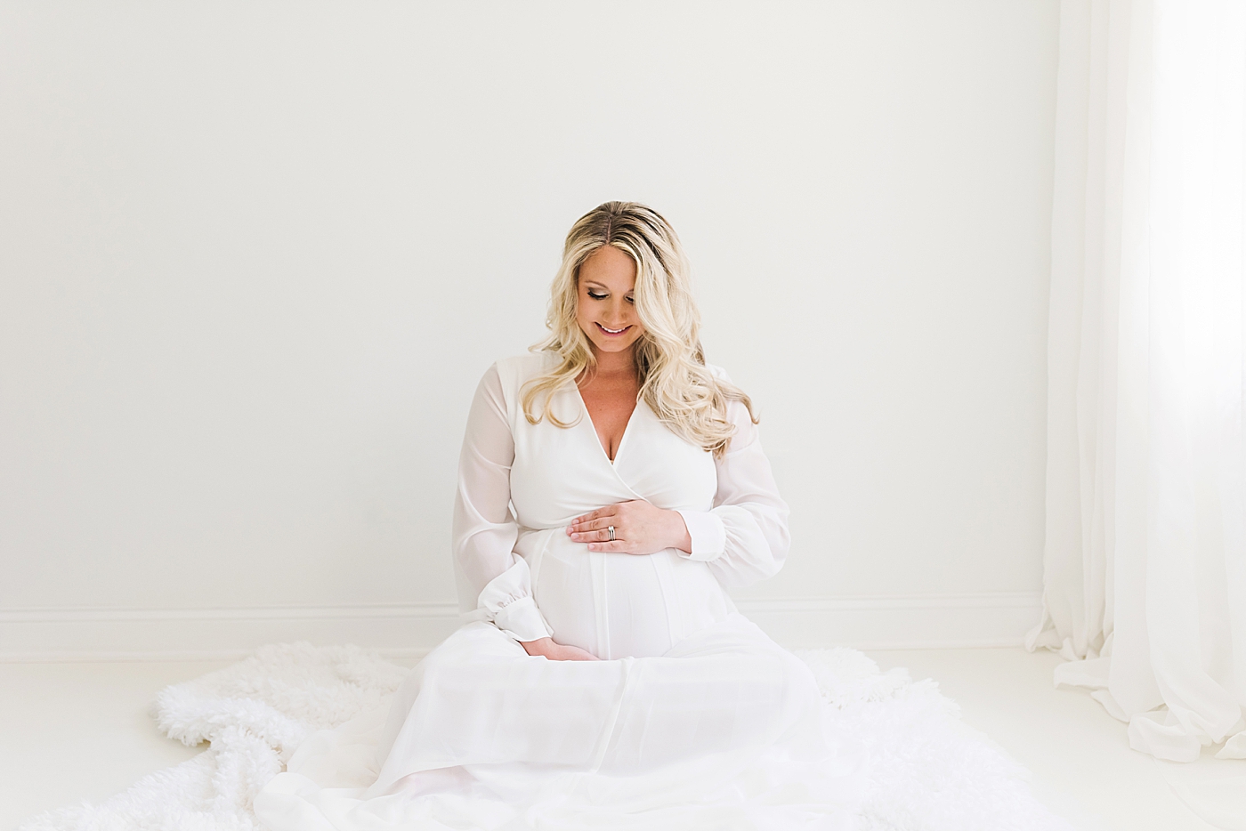 Pregnant woman in white dress sitting on the floor | Photo by Huntersville Newborn Photographer Anna Wisjo 