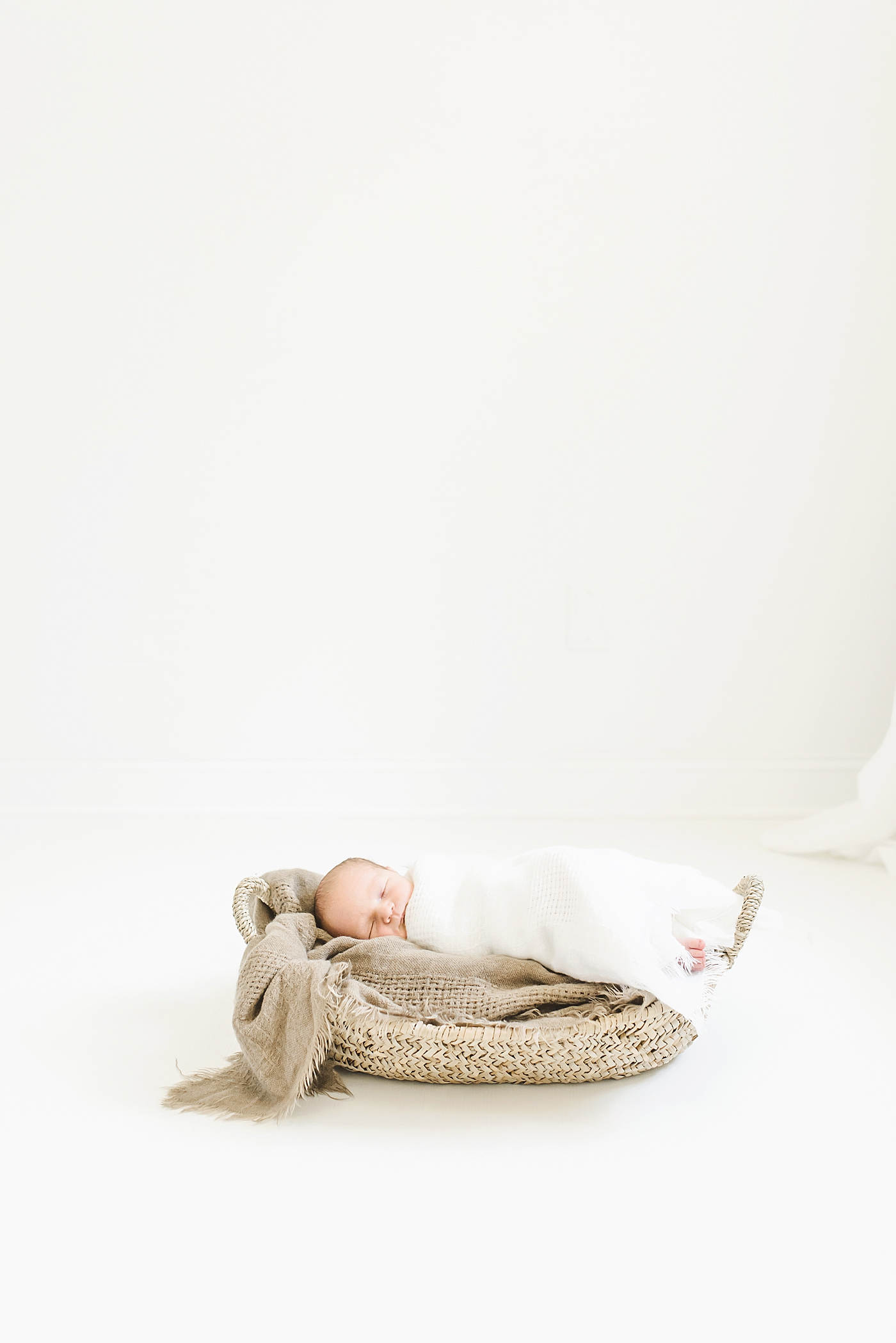 Baby boy wrapped in swaddle sleeping in a basket | Photo by Anna Wisjo Photography