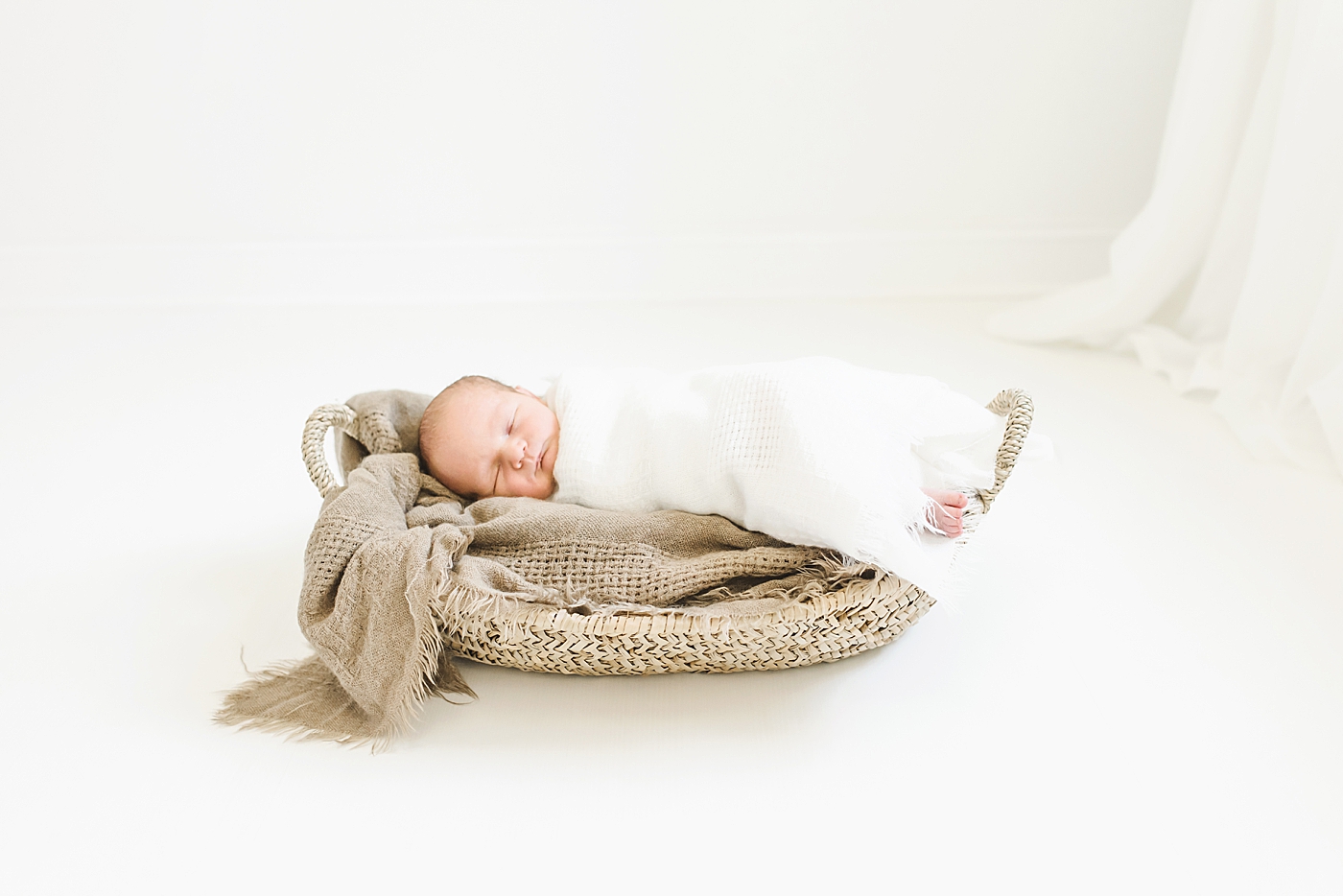 Newborn baby sleeping wrapped in swaddle | Photo by Anna Wisjo Photography