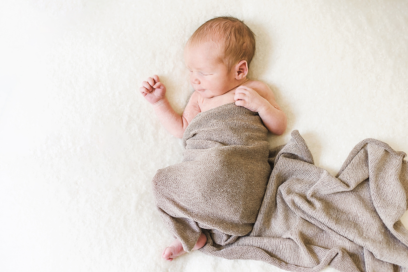 Newborn baby wrapped in tan swaddle | Photo by Anna Wisjo Photography