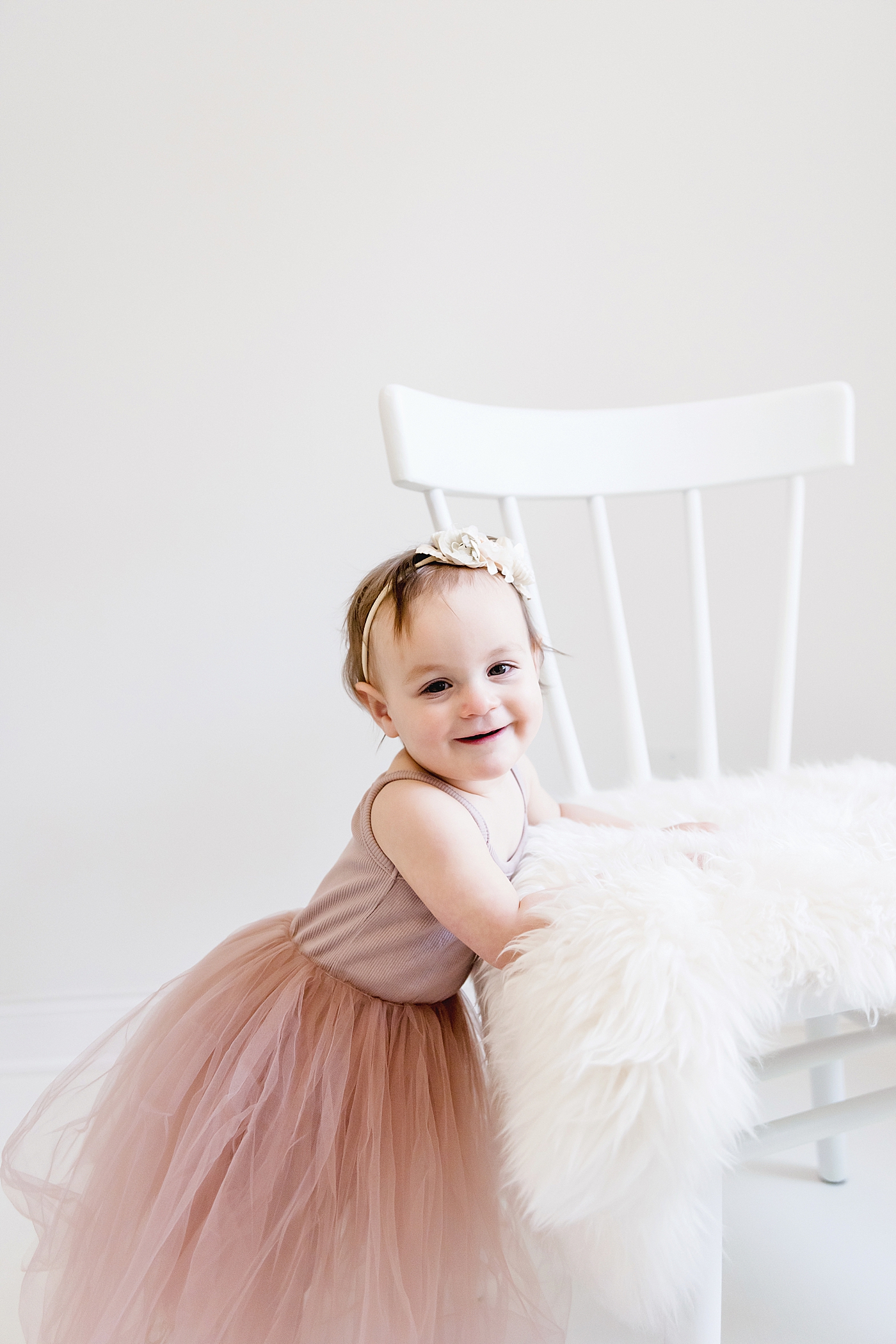 Toddler girl in pink tutu standing beside white chair | Photo by Huntersville Baby Photographer Anna Wisjo 