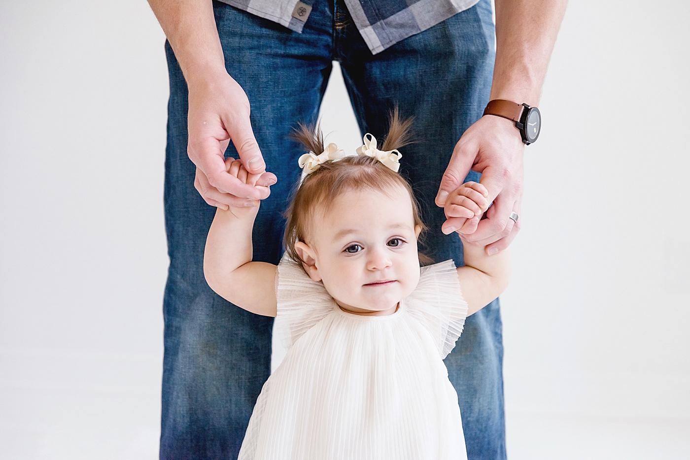 Dad holding baby girls hands helping her walk | Photo by Anna Wisjo Photography
