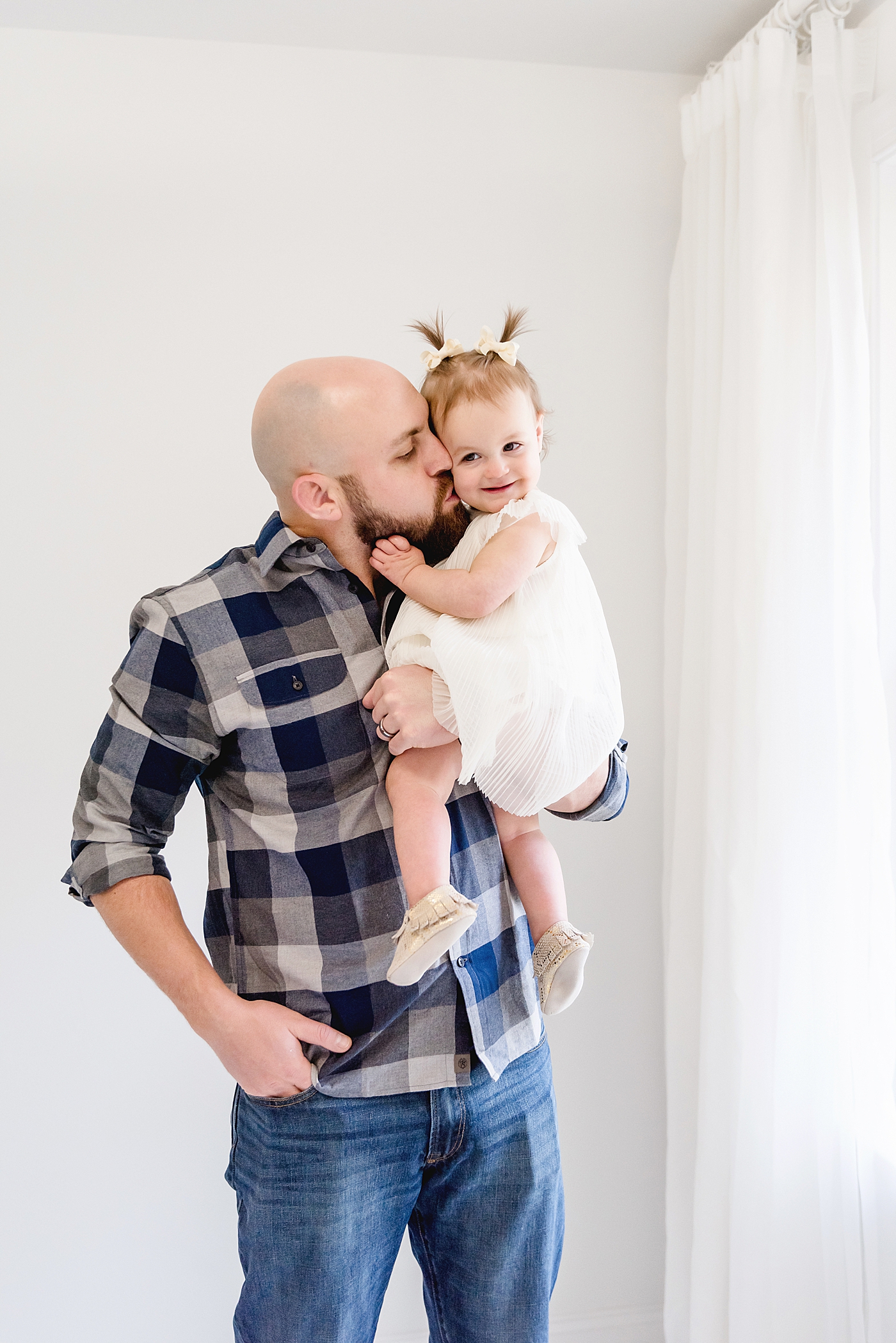 Dad in blue giving baby girl a kiss on the cheek | Photo by Anna Wisjo Photography