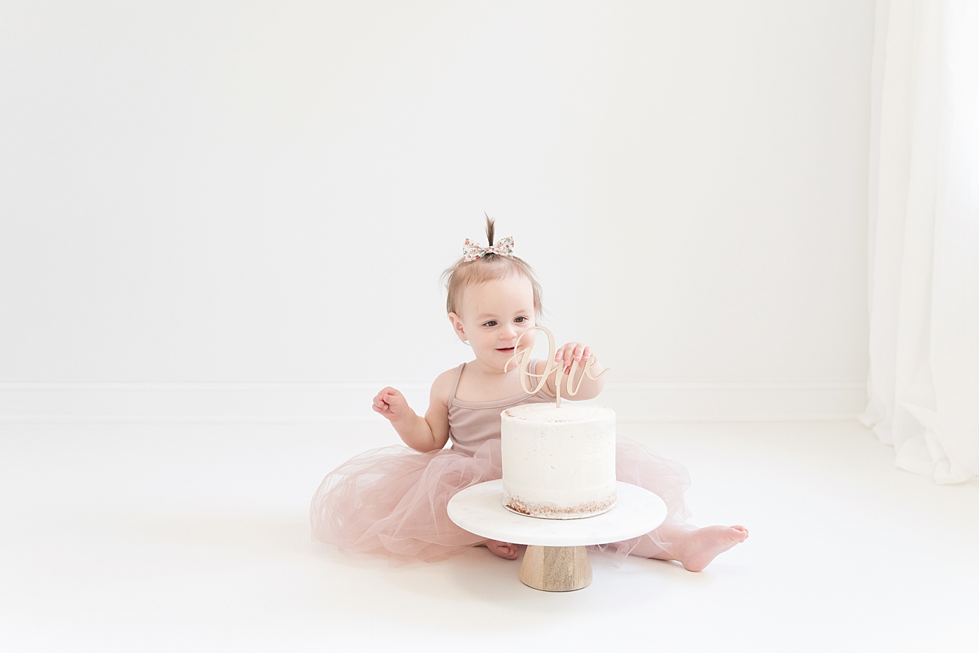 Baby girl playing with cake decorations on smash cake | Photo by Anna Wisjo Photography