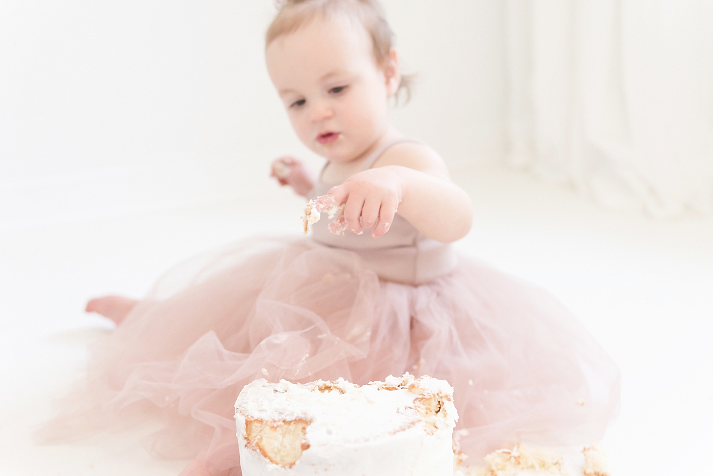 Baby girl putting finger in cake | Photo by Anna Wisjo Photography