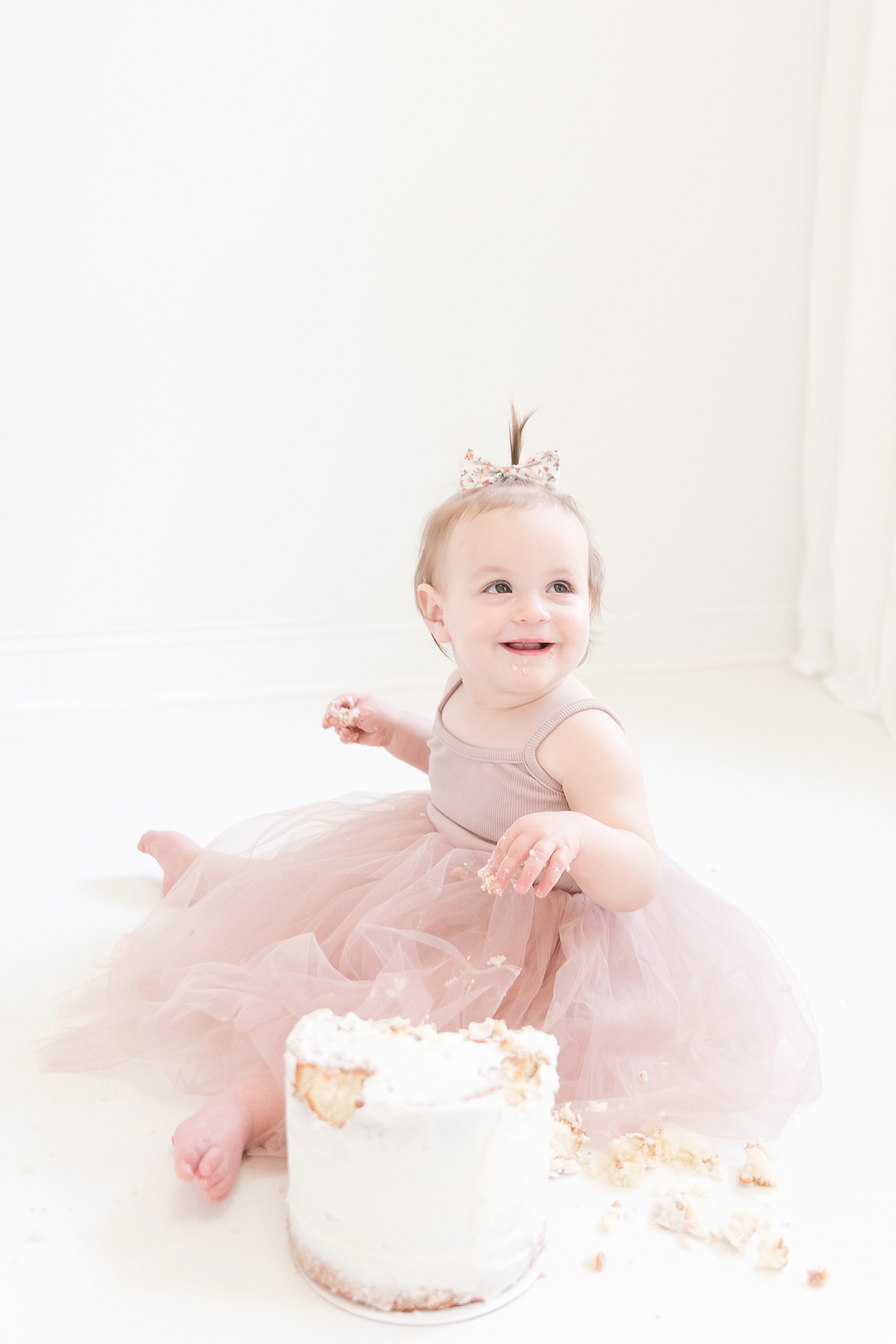 Baby girl in pink smiling while eating cake | Photo by Huntersville Baby Photographer Anna Wisjo 