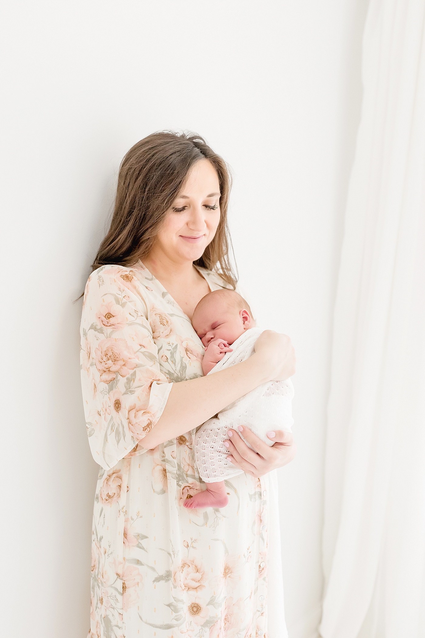 Mom in a floral print dress holding newborn | Photo by Anna Wisjo Photography