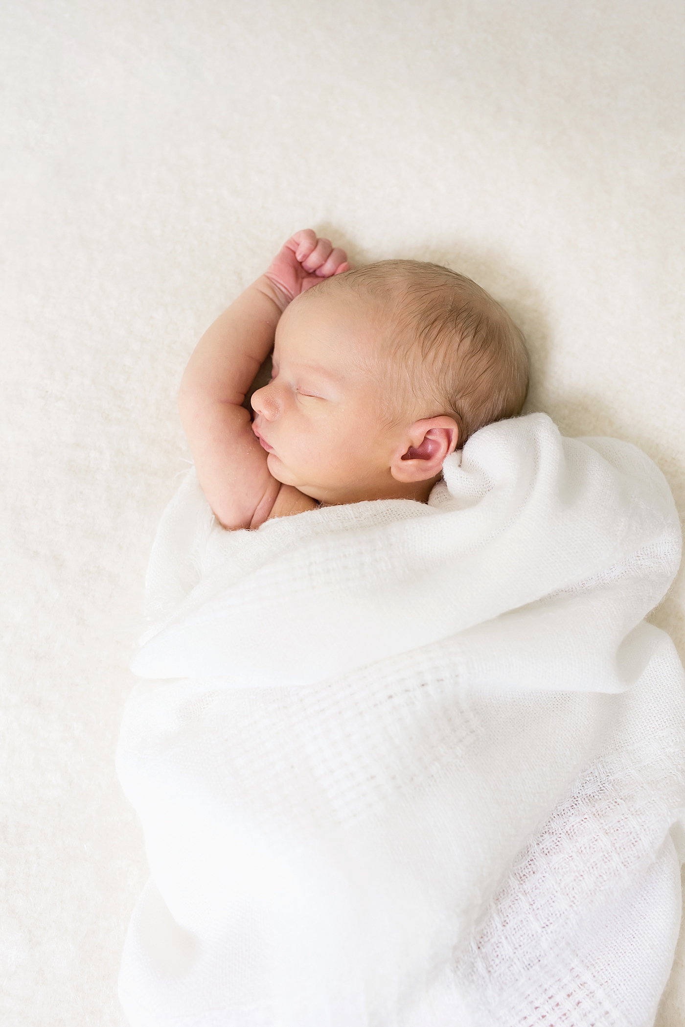 Sleeping newborn baby with arm out of her swaddle | Photo by Huntersville NC Newborn Photographer Anna Wisjo