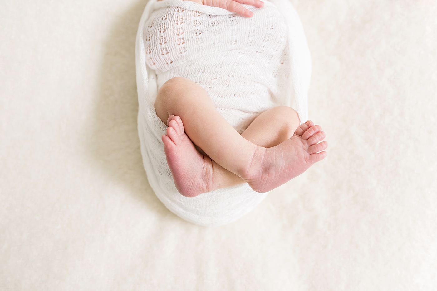 Detail photo of newborn baby girl wrapped in white swaddle | Photo by Anna Wisjo Photography