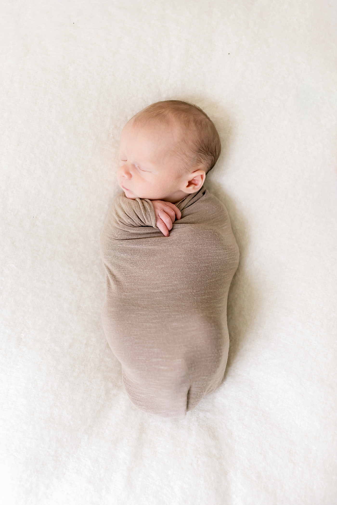 Baby boy sleeping wrapped in brown swaddle | Photo by Charlotte NC Newborn Photographer Anna Wisjo