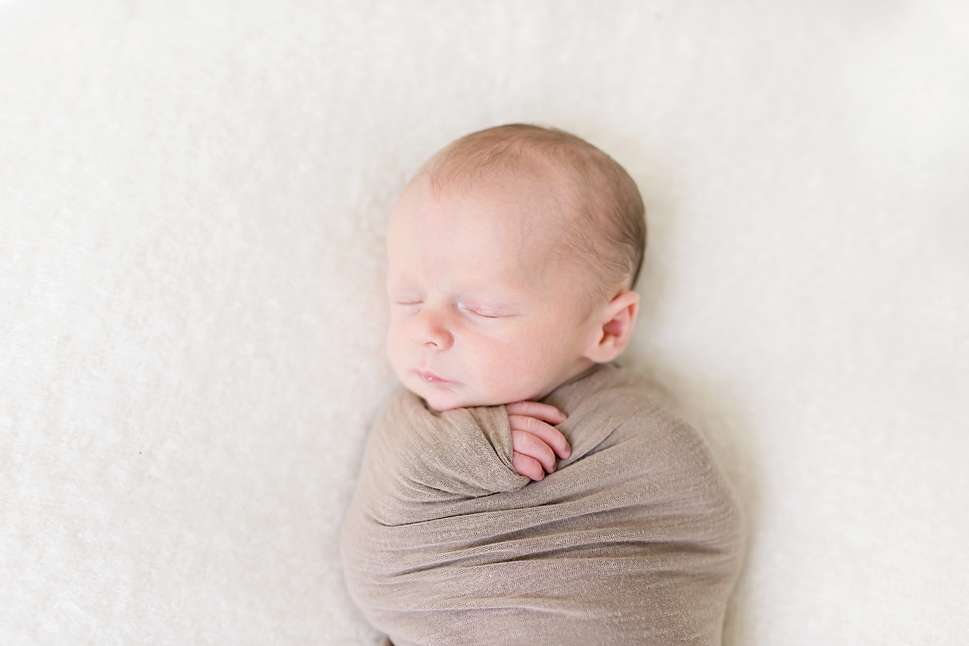 Baby boy sleeping wrapped in brown swaddle | Photo by Anna Wisjo