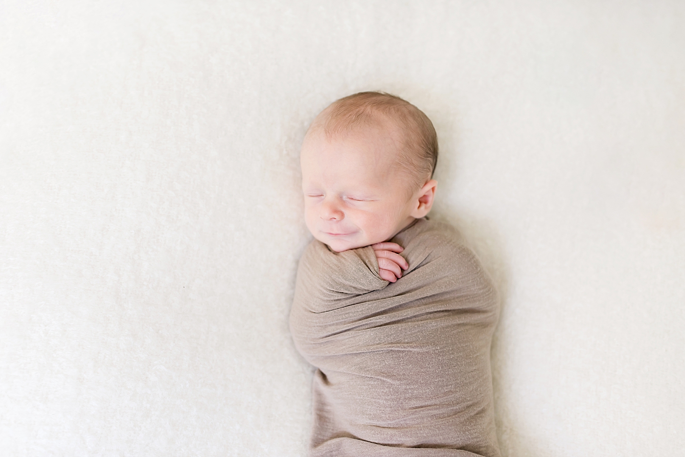 Baby boy wrapped in brown swaddle | Photo by Anna Wisjo