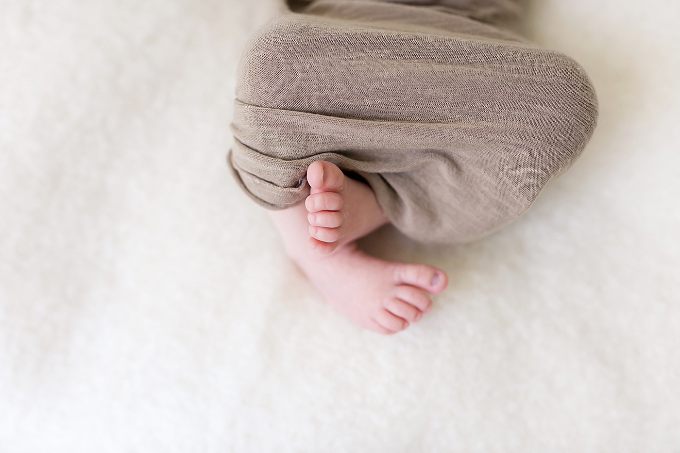 Newborn baby toes wrapped in beige swaddle | Photo by Anna Wisjo