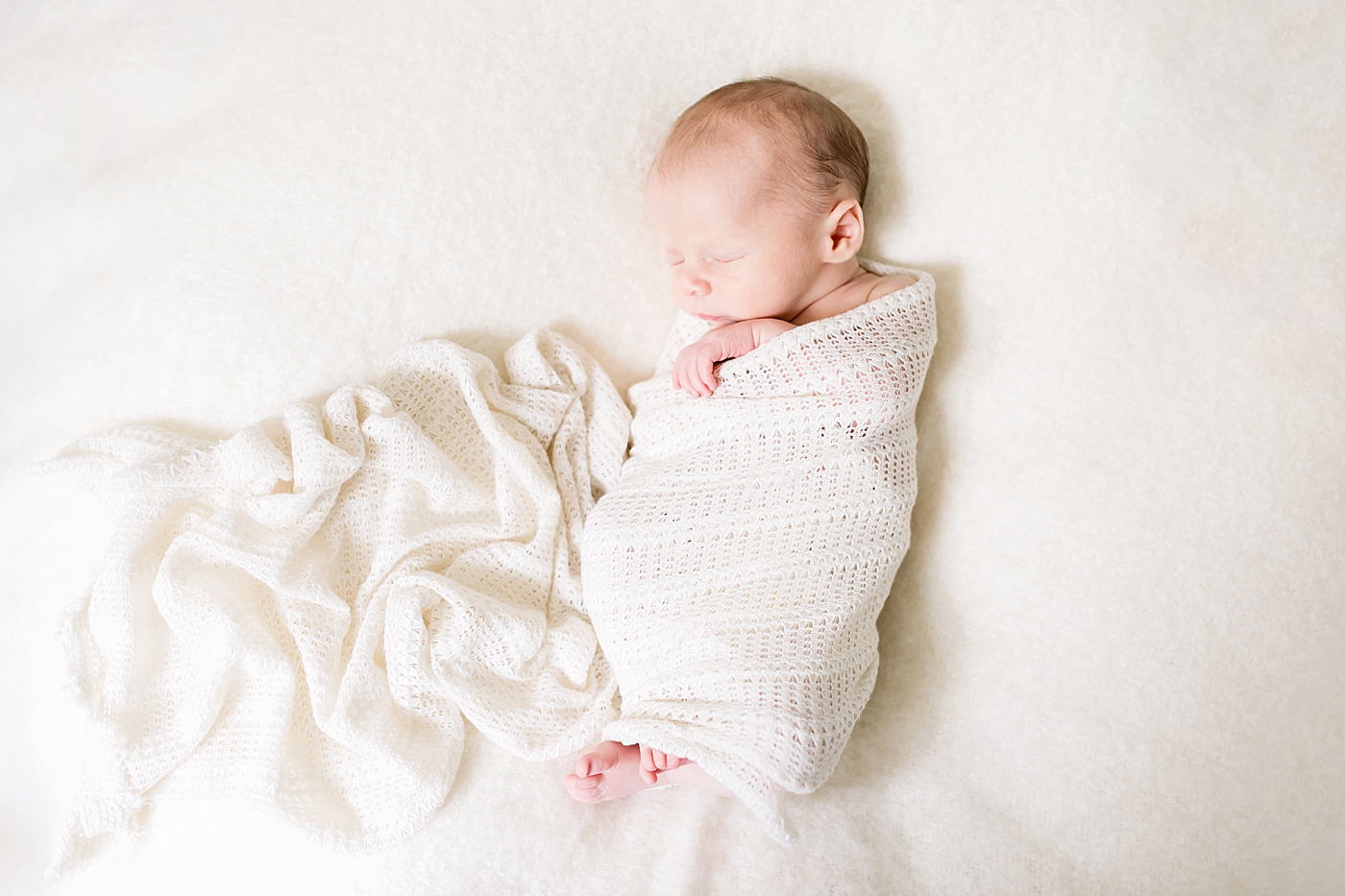 Newborn sleeping on cream surface with swaddle | Photo by Charlotte NC Newborn Photographer Anna Wisjo