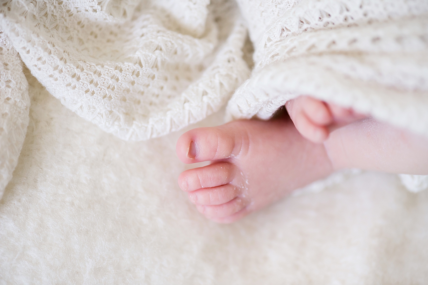 Newborn baby feet and white blanket | Photo by Anna Wisjo