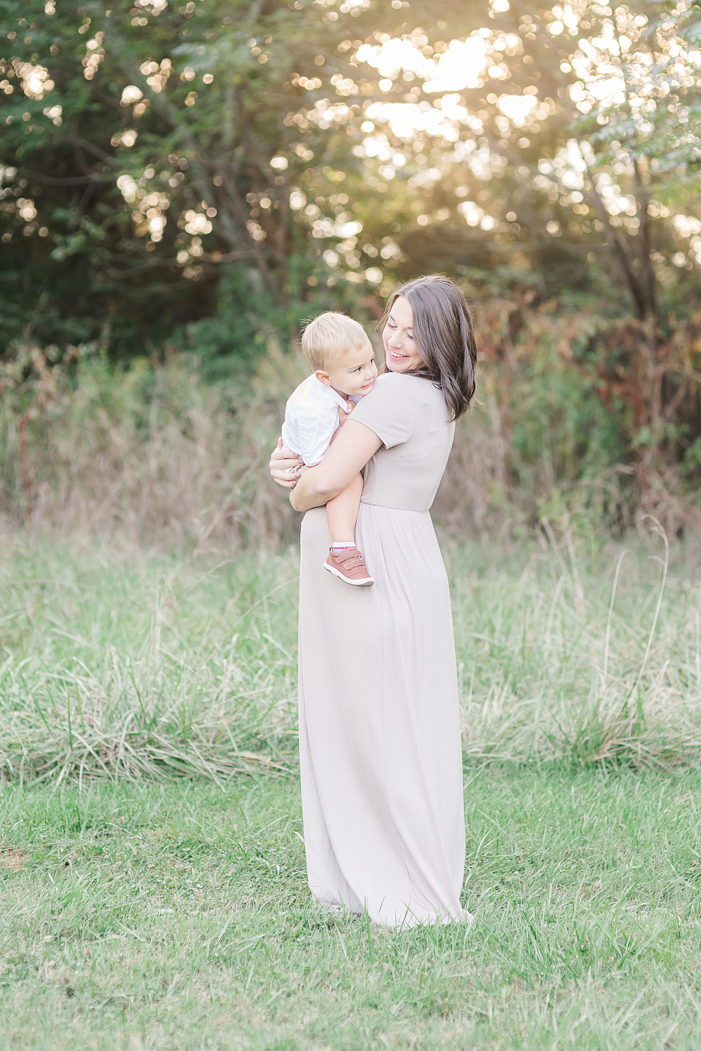 Pregnant mom holding toddler boy | Photo by Anna Wisjo