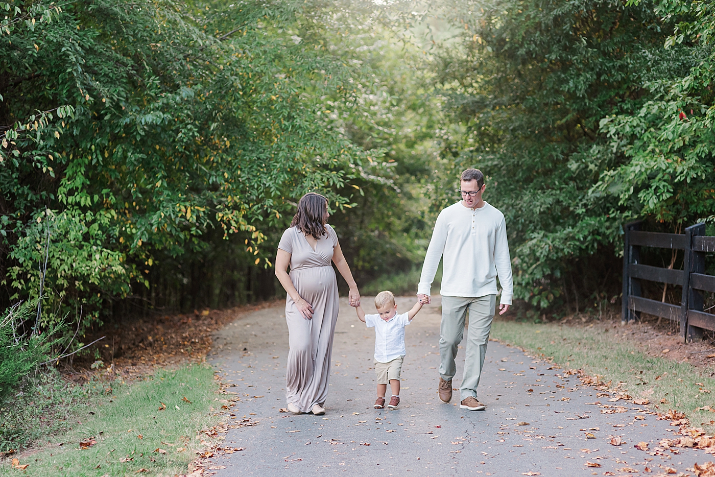 Expectant mom and dad walking with toddler | Photo by Anna Wisjo Photography