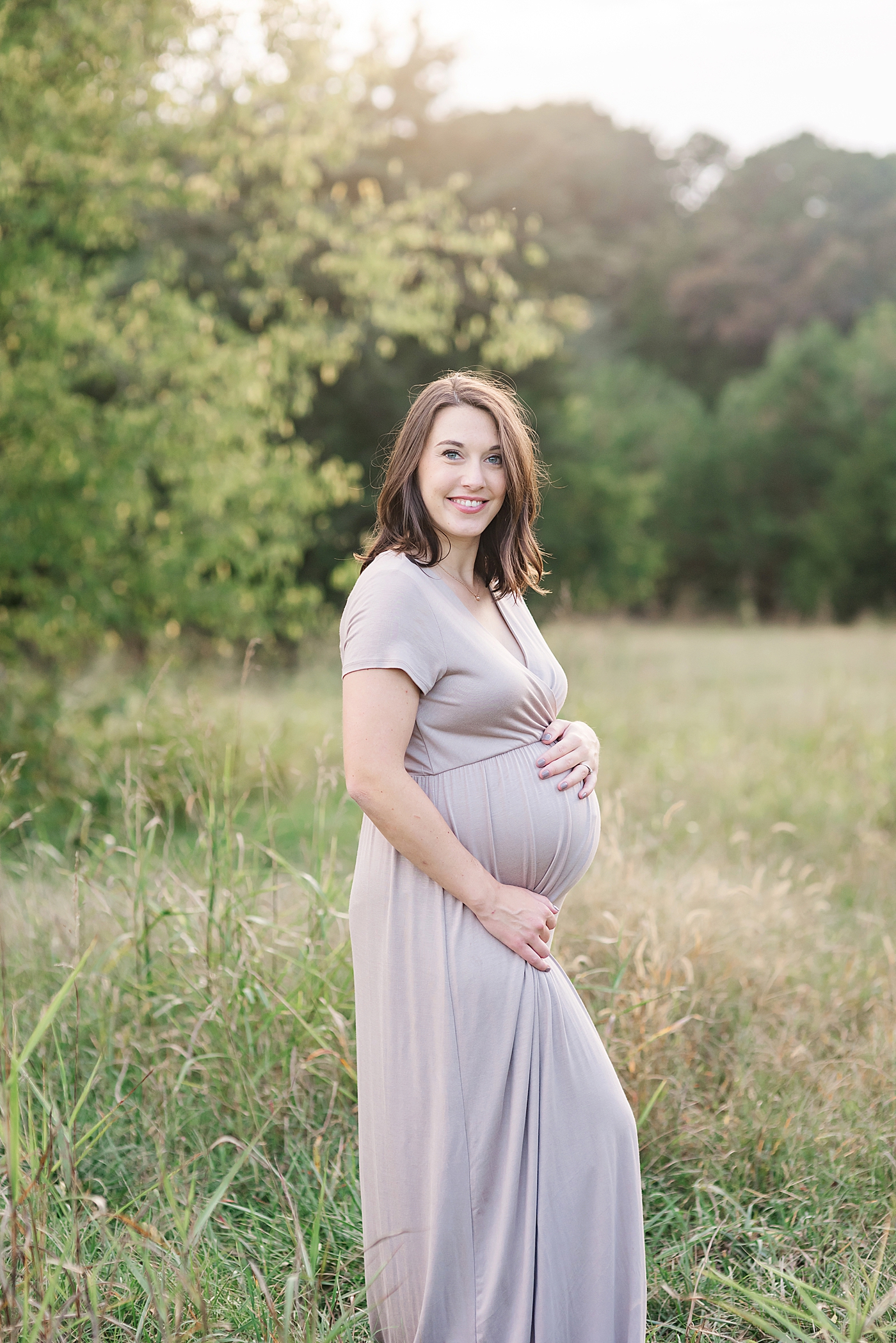 Expectant mom in mauve dress smiling | Photo by Anna Wisjo