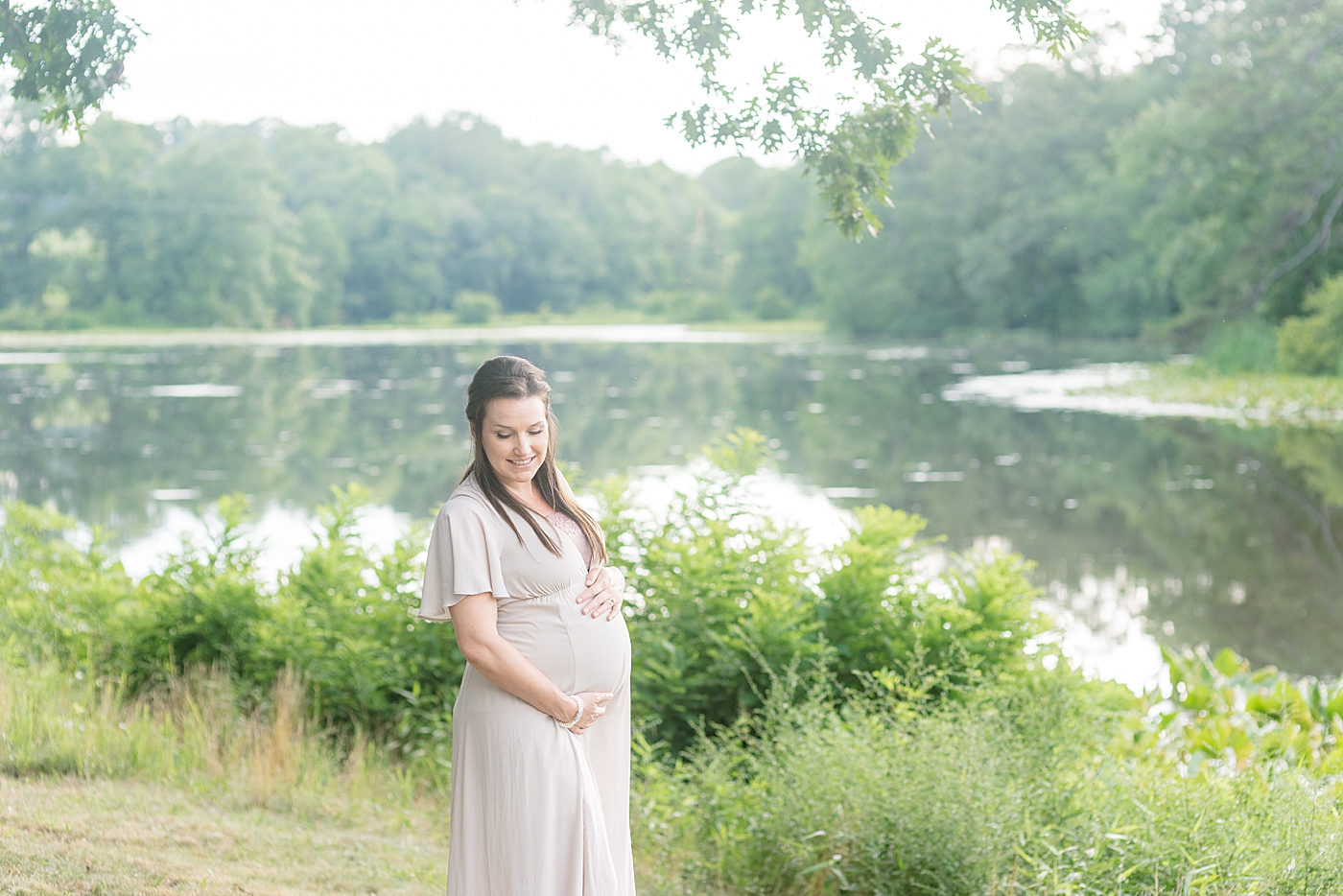 Mother to be in a field cradling her belly | Photo by Anna Wisjo Photography