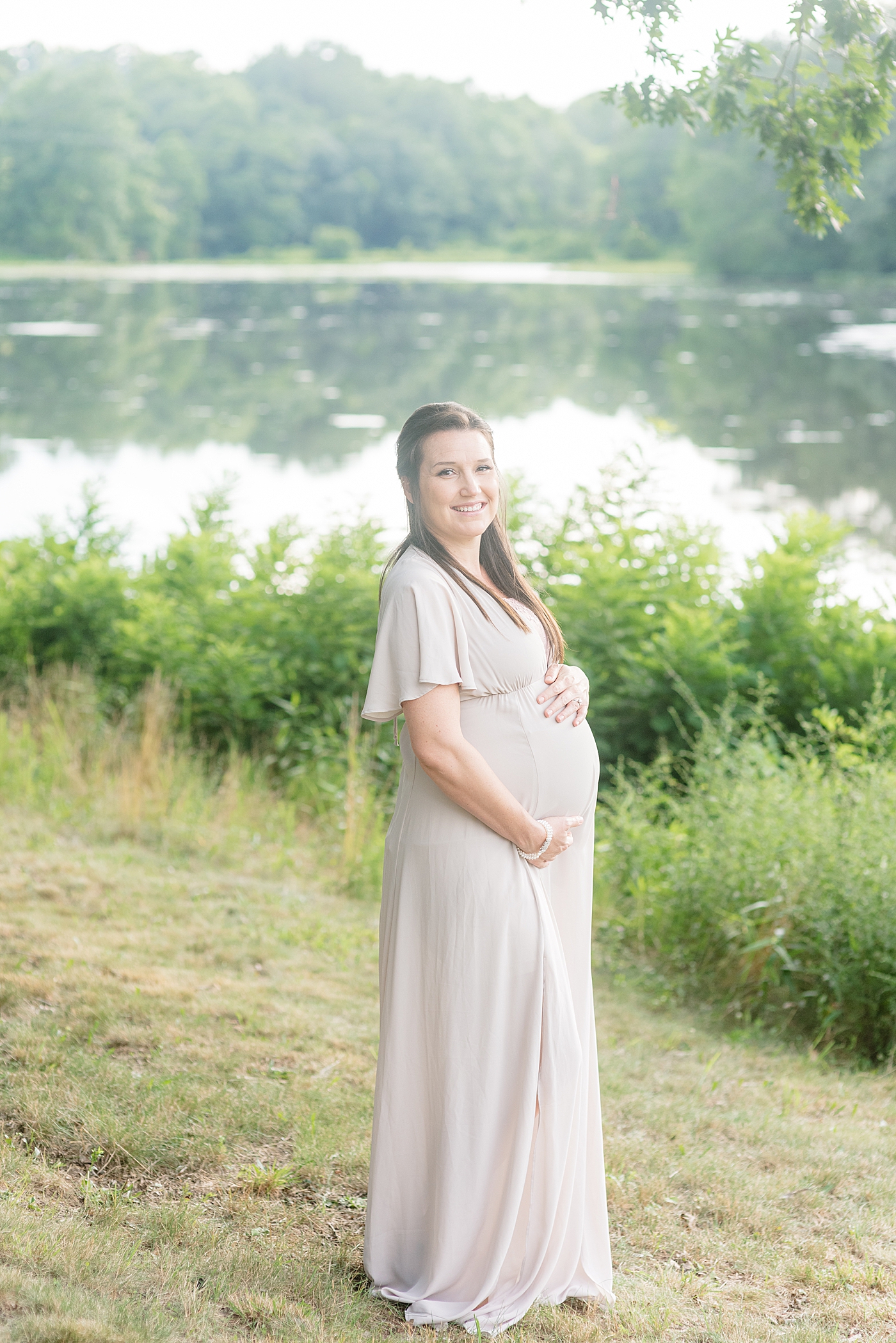 Mom to be in flowing dress in front of a pond | Photo by Anna Wisjo Photography