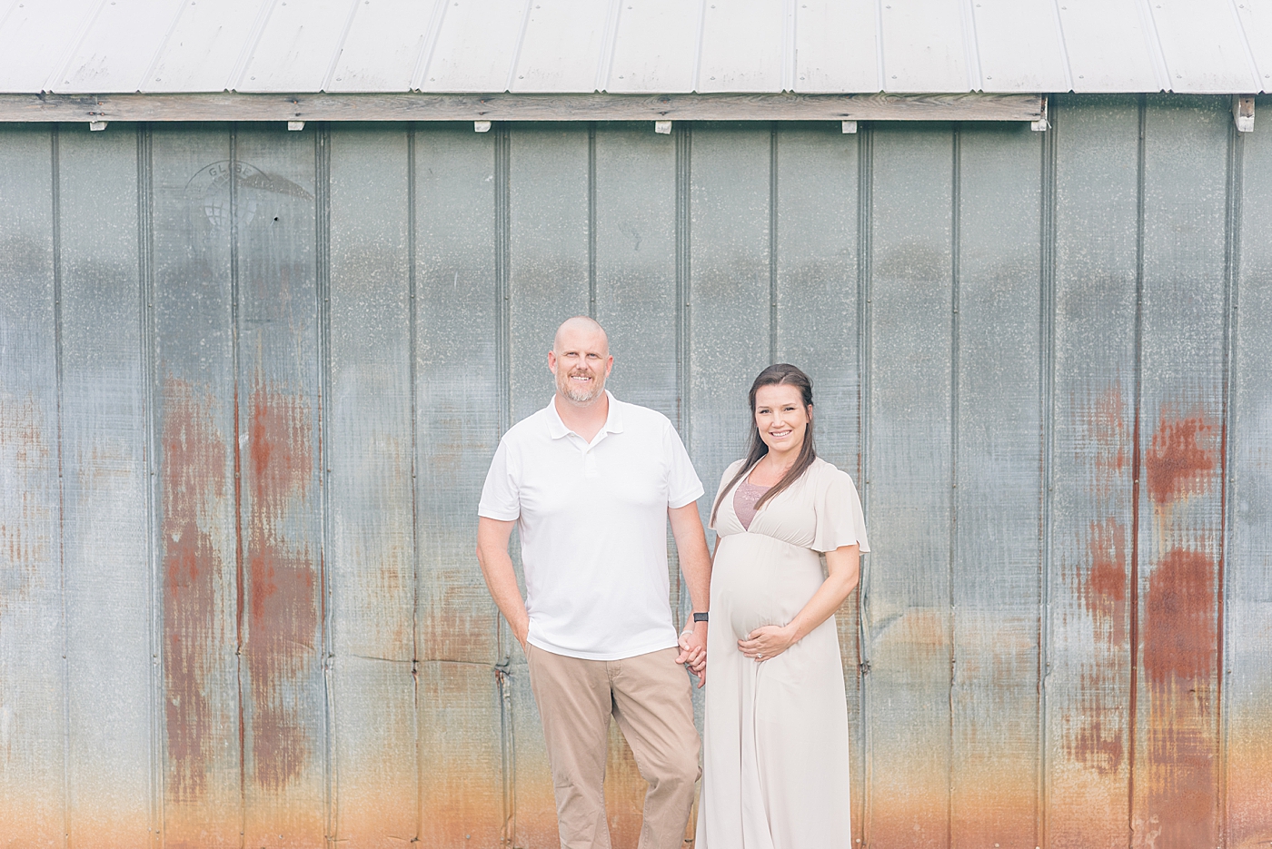 Mom and dad holding hands in front of a barn | Photo by Anna Wisjo Photography