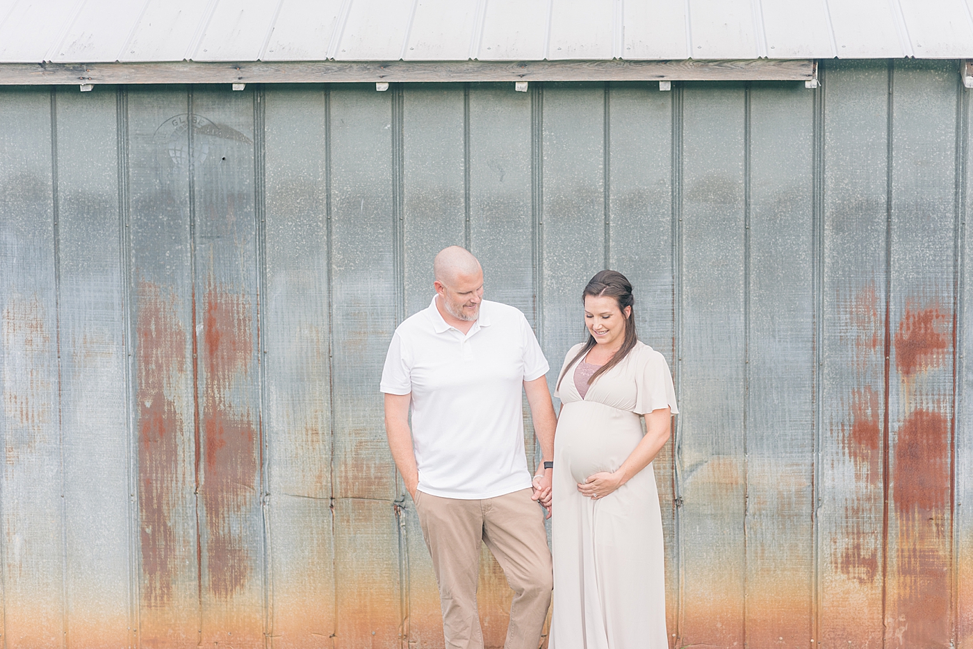 Mom and dad to be walking in front of a barn | Photo by Anna Wisjo Photography