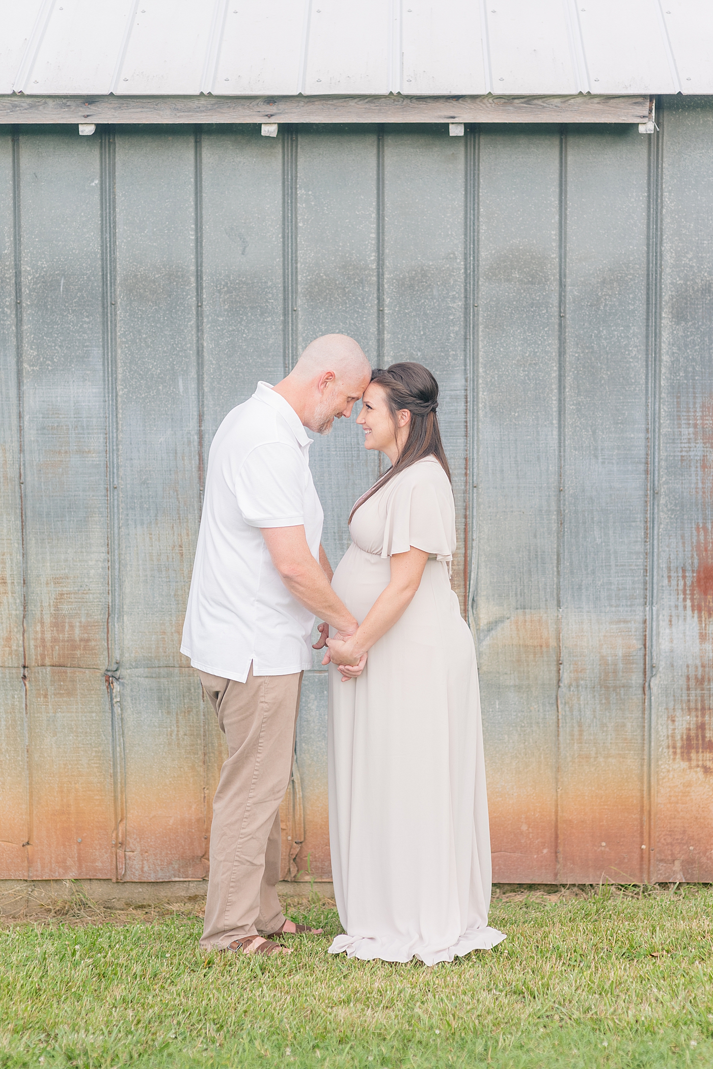 Mom and dad to be holding hands with foreheads together | Photo by Anna Wisjo Photography