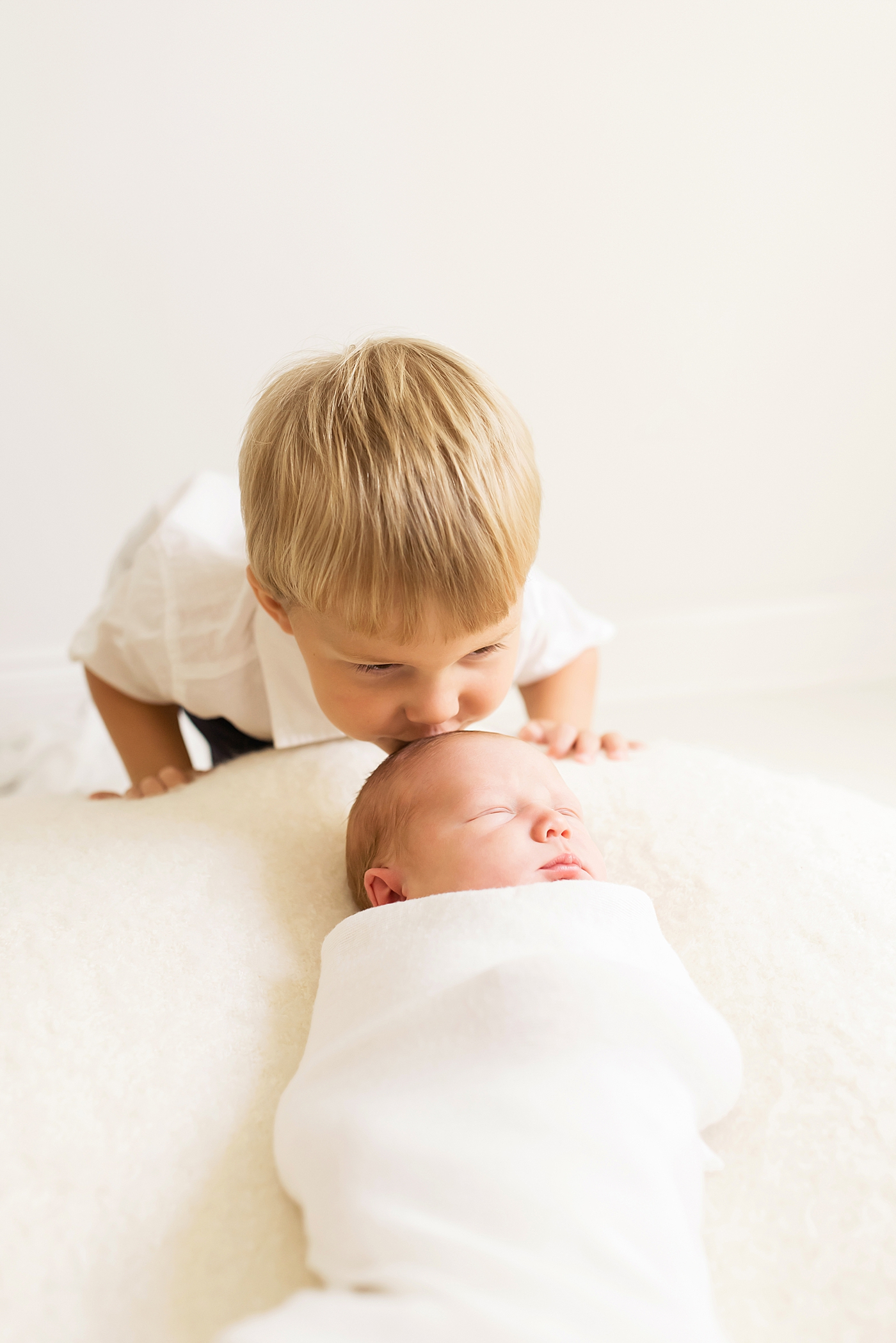 Big brother kissing newborn baby brother on the head | Photo by Anna Wisjo Photography 