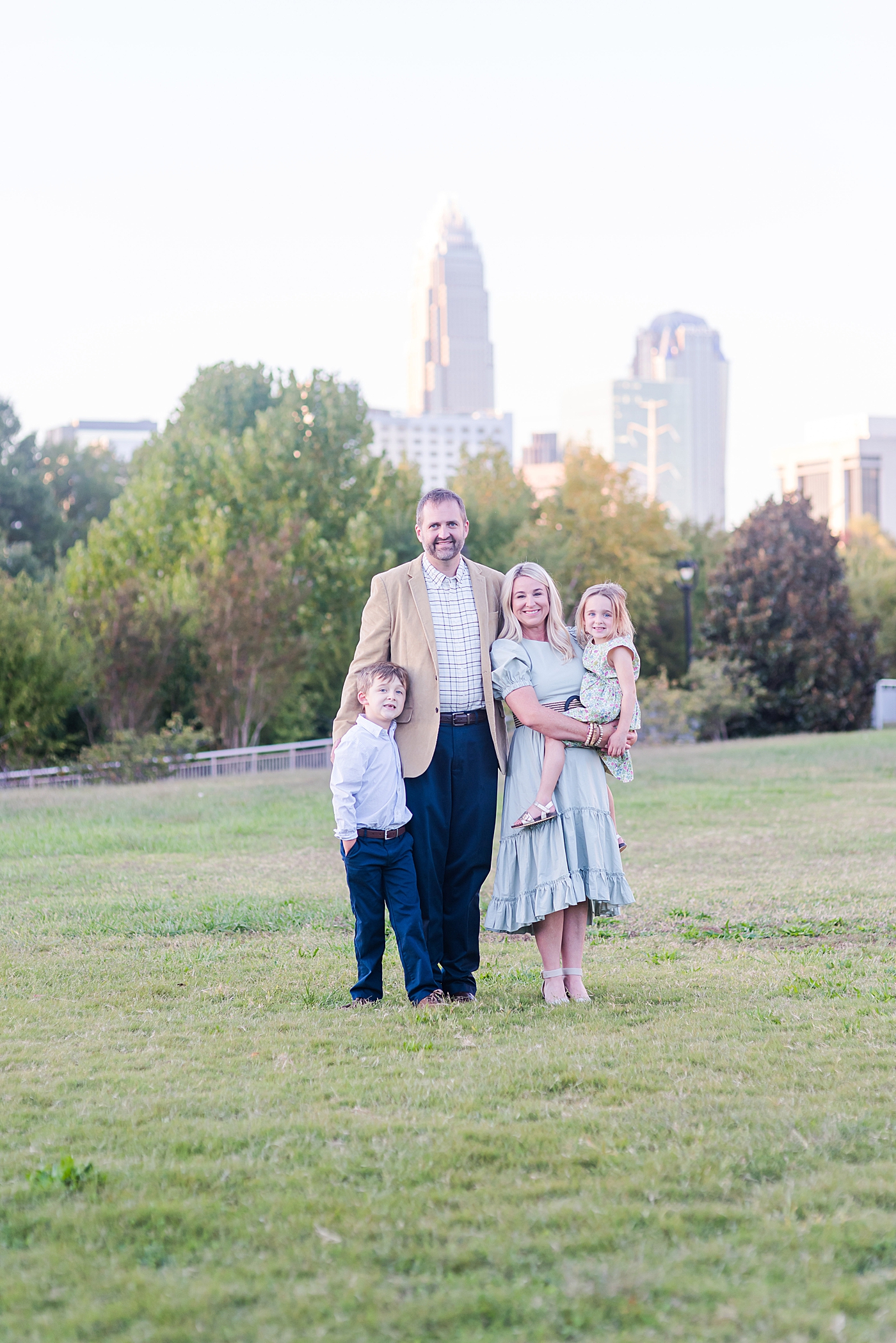 Family standing in a park in front of Charlotte skyline | Photo by Anna Wisjo Photography