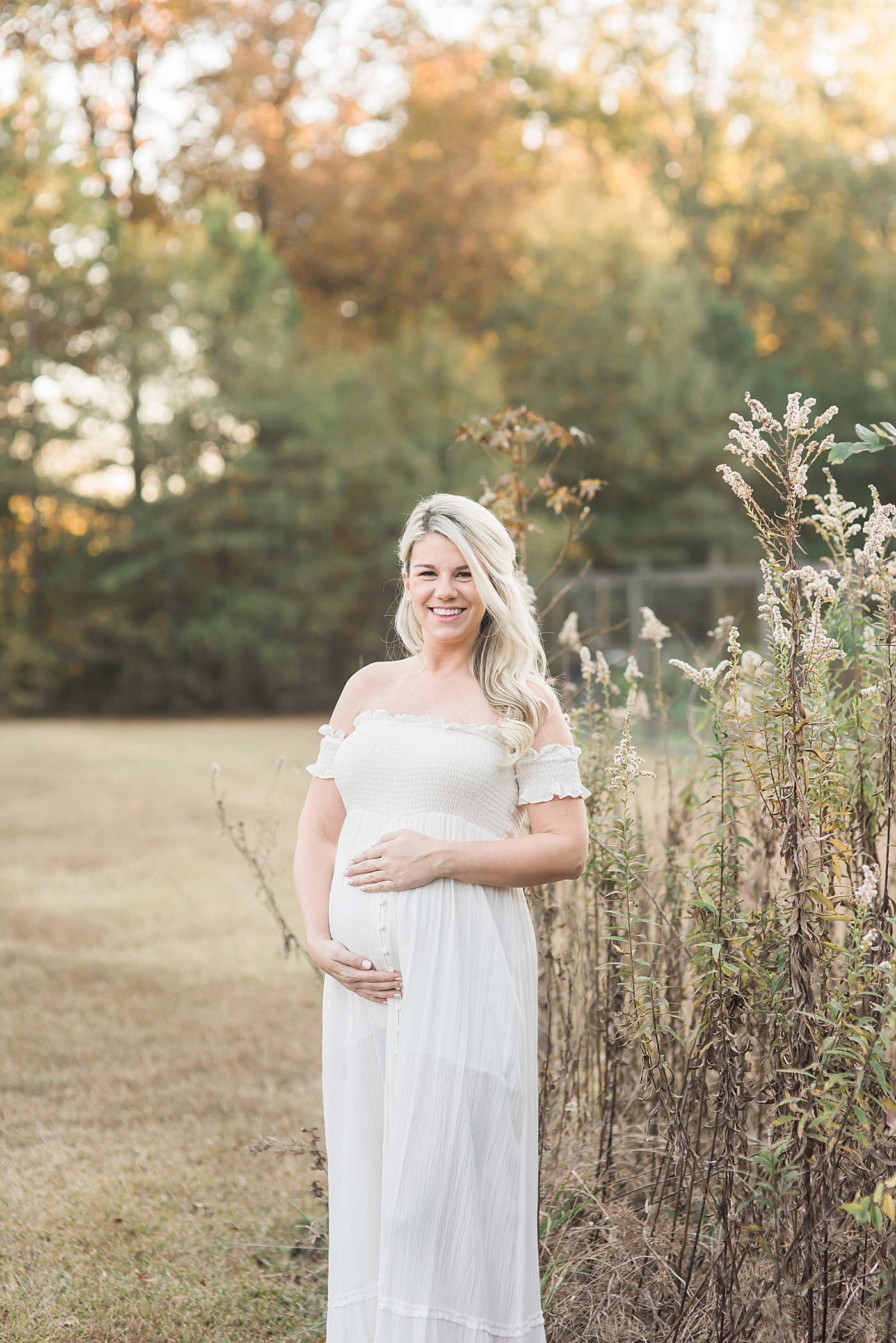 Young mother to be in white cradling her belly | Photo by Charlotte Maternity Photographer Anna Wisjo 