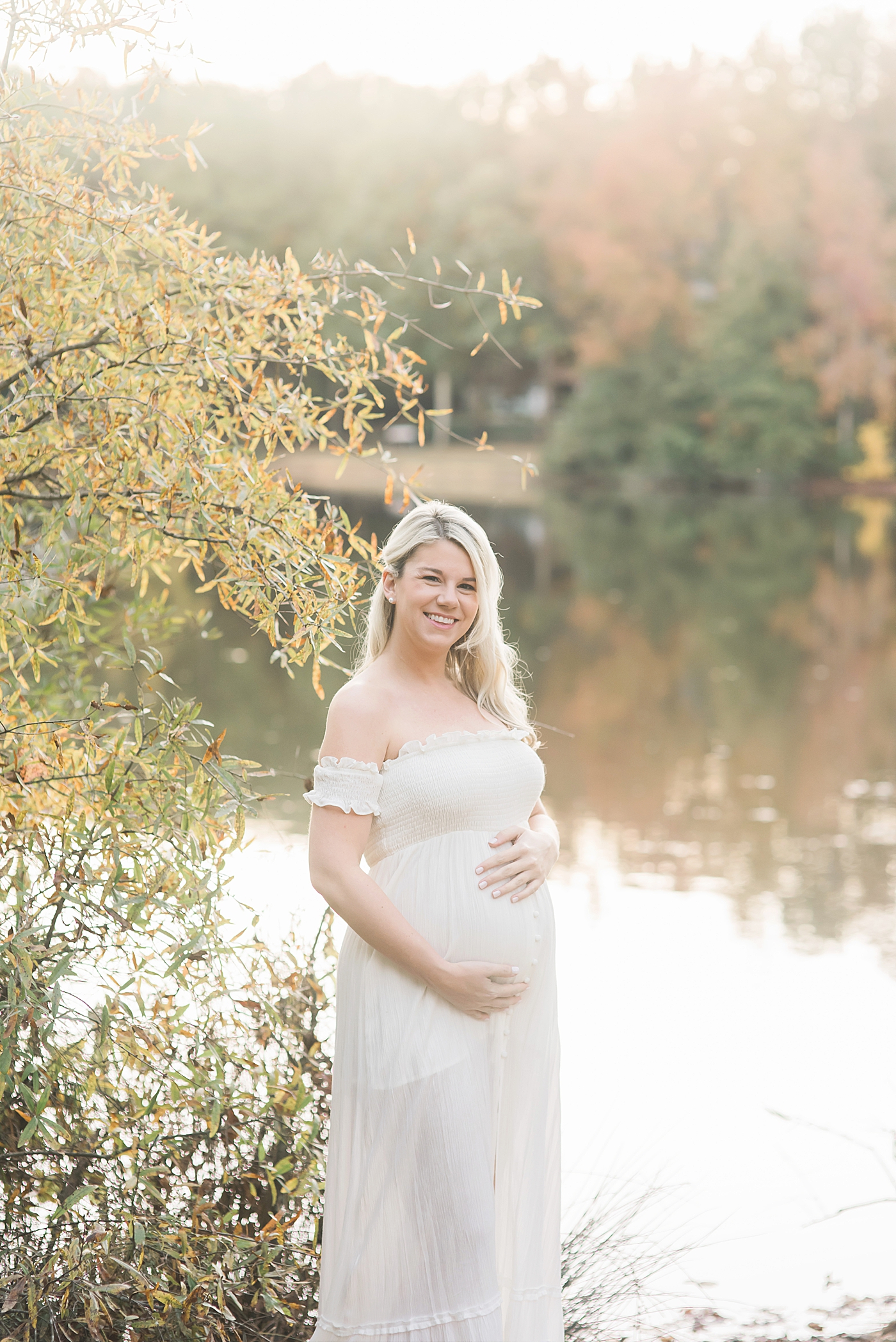 Smiling mother to be in long white dress | Photo by Anna Wisjo 