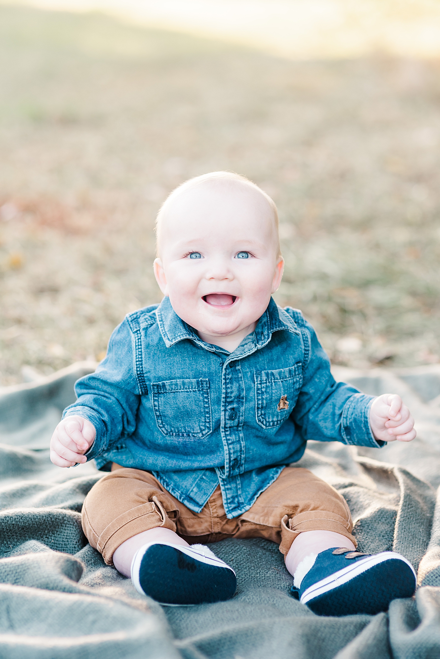 Baby boy with blue eyes sitting on a blanket in the grass | Photo by Anna Wisjo Photography