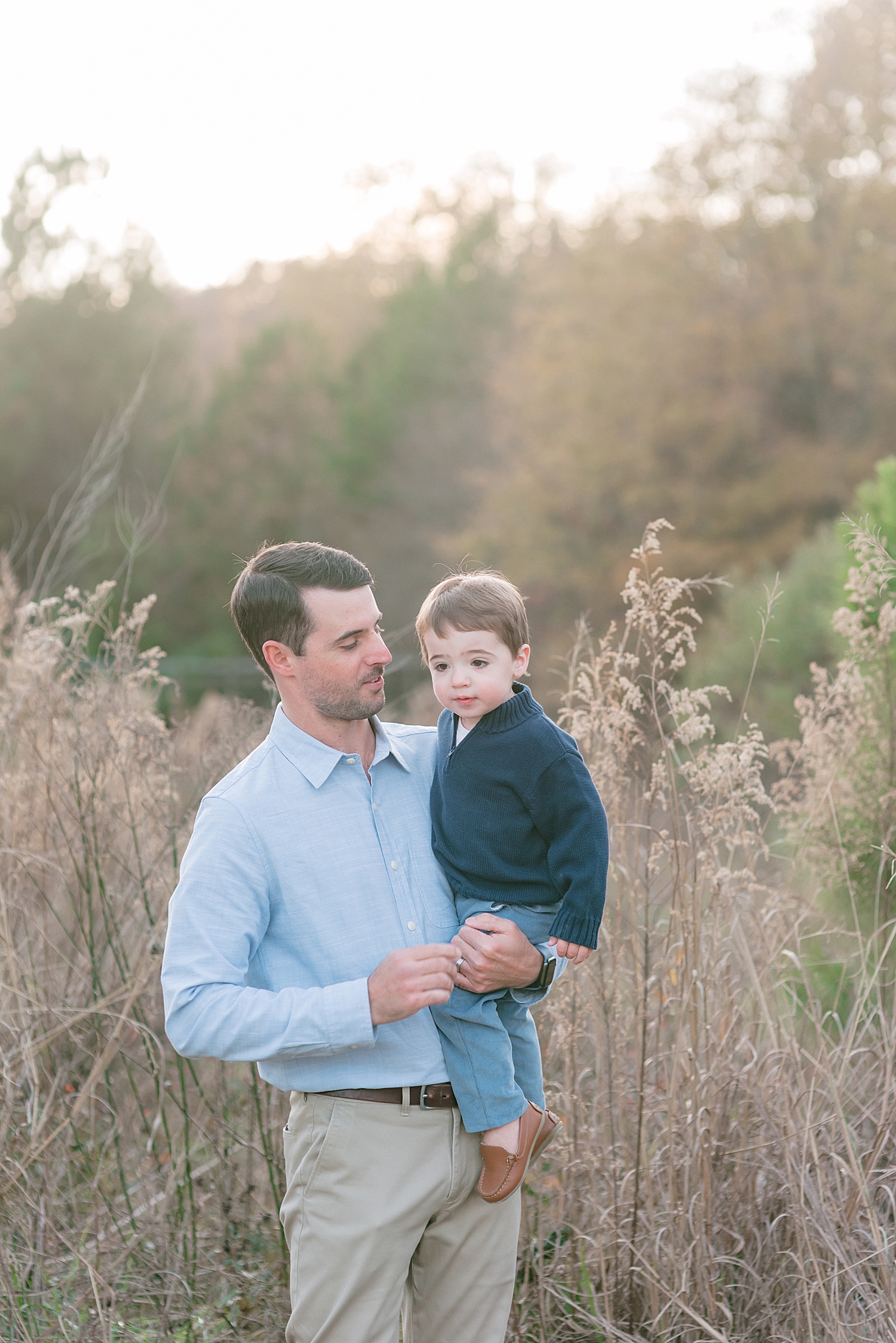 Dad holding his toddler boy in navy at Milestone Session at Marvin Efird Park | Photo by Anna Wisjo Photography 
