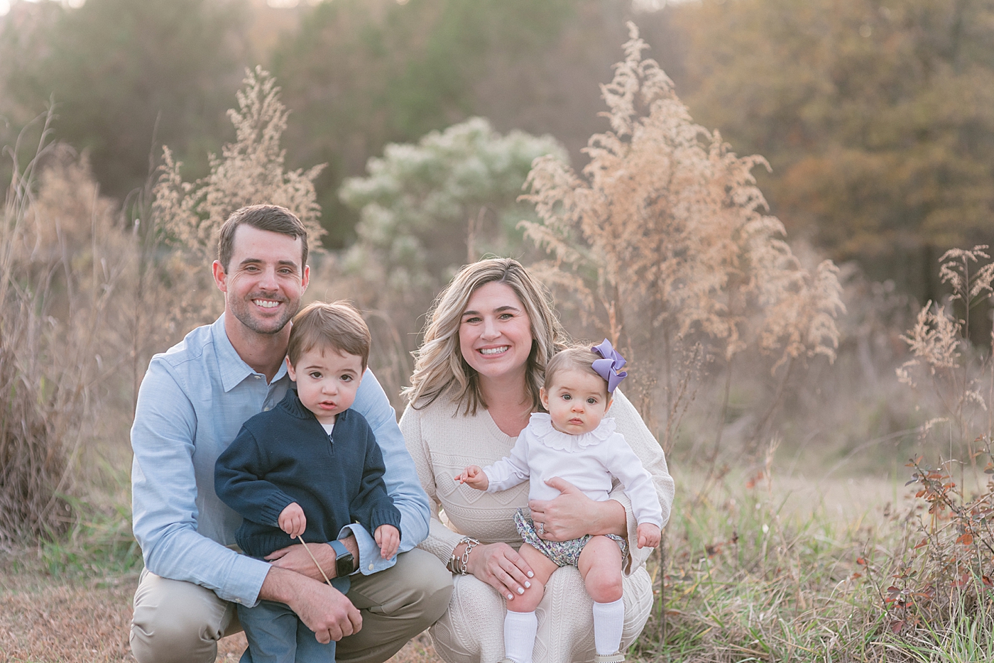 Family of four sitting together in a field at sunset during family session Milestone Session at Marvin Efird Park | Photo by Anna Wisjo Photography 