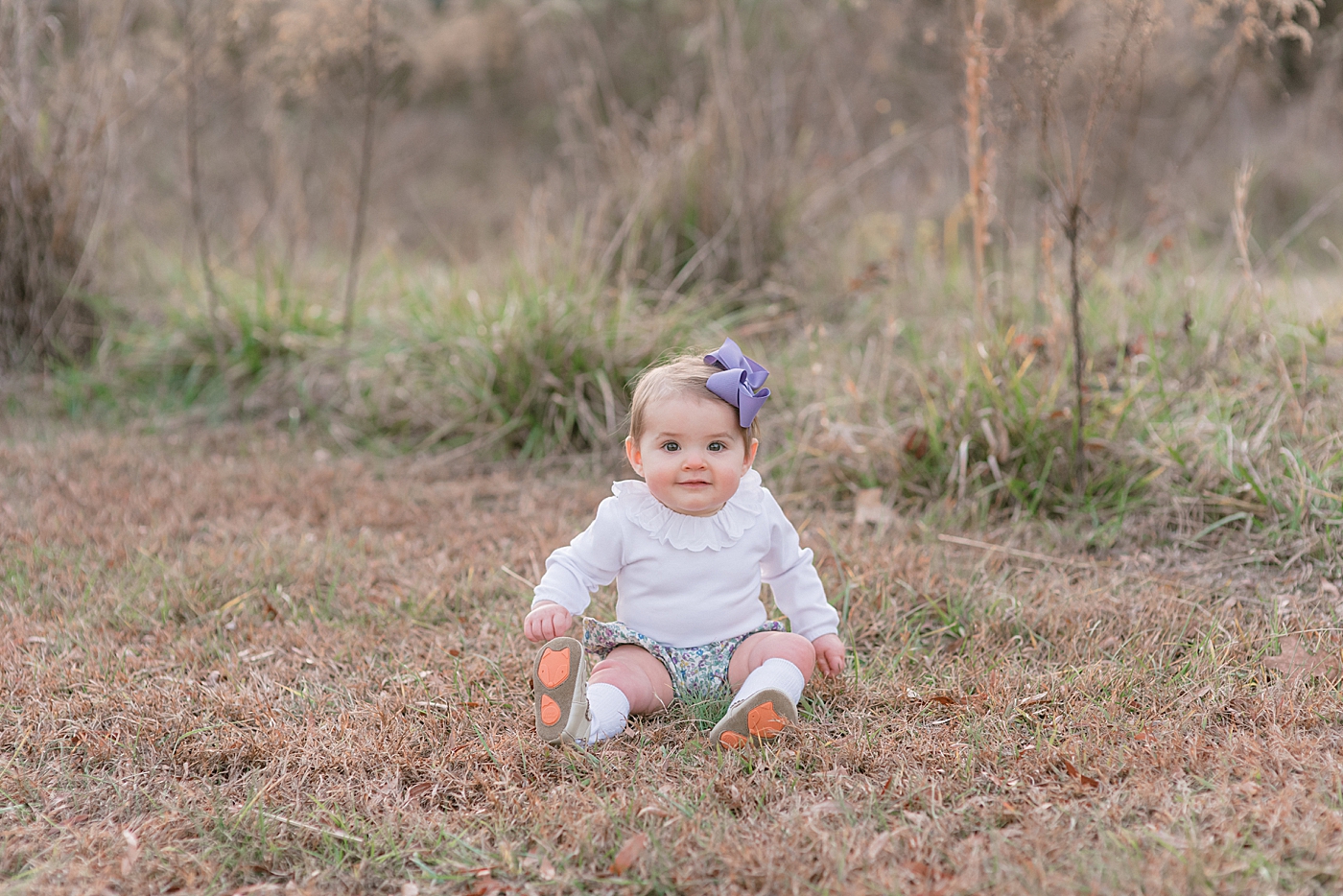 Baby girl sitting in a field during her Milestone Session in Charlotte | Photo by Anna Wisjo Photography 