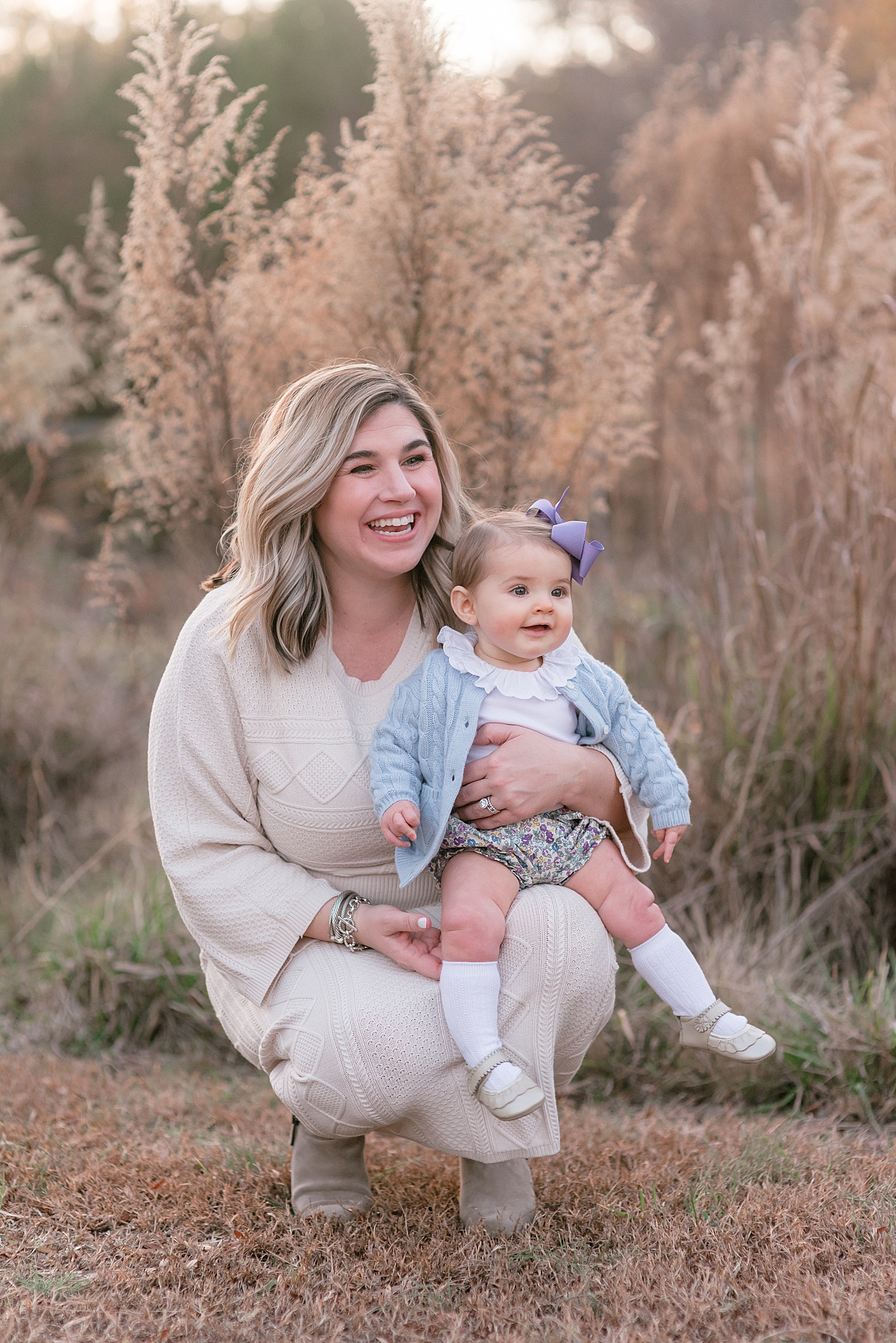Mom with her baby girl sitting in a field during her Milestone Session at Marvin Efird Park | Photo by Anna Wisjo Photography 