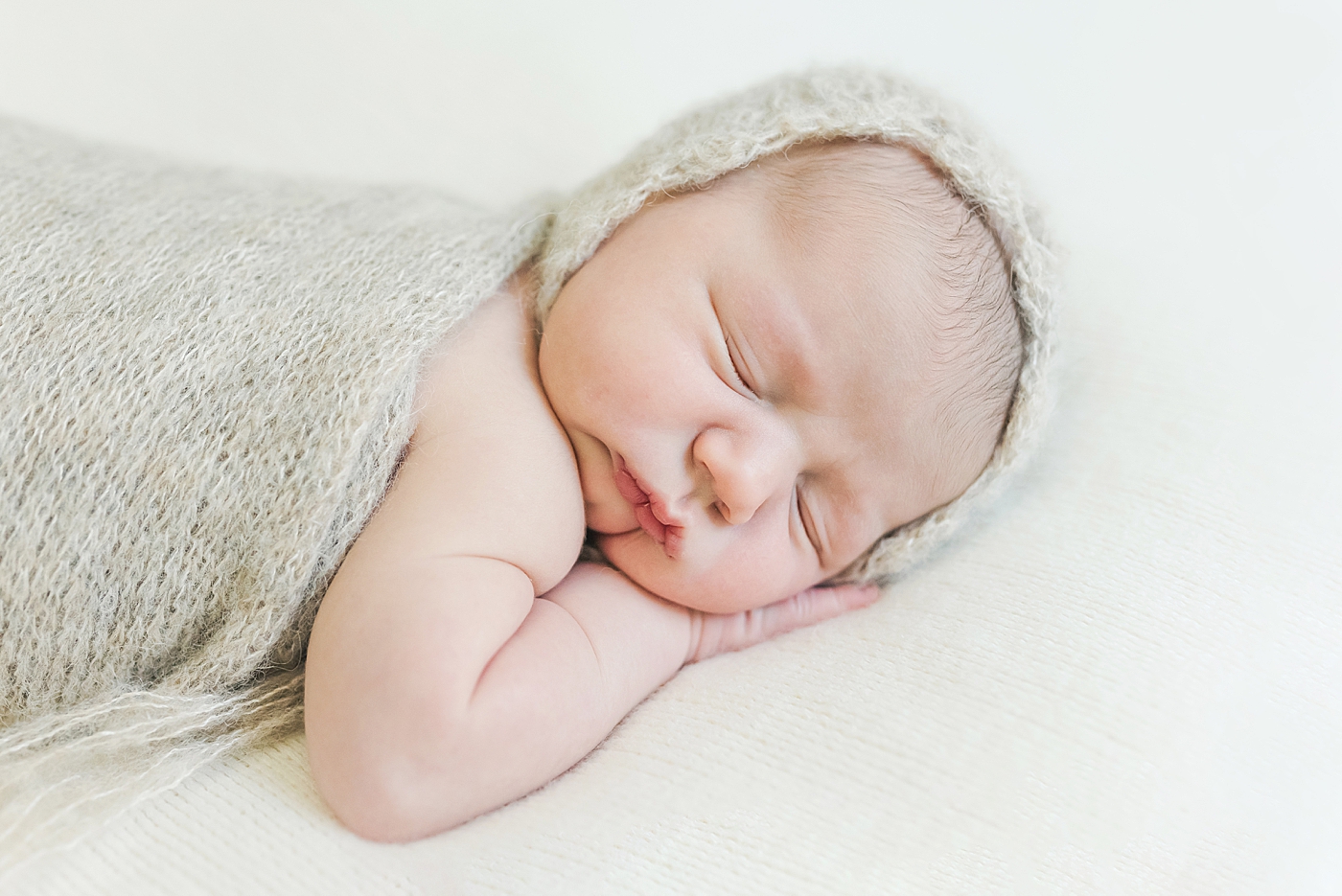 Sleeping newborn with bonnet and swaddle | Photo by Anna Wisjo Photography