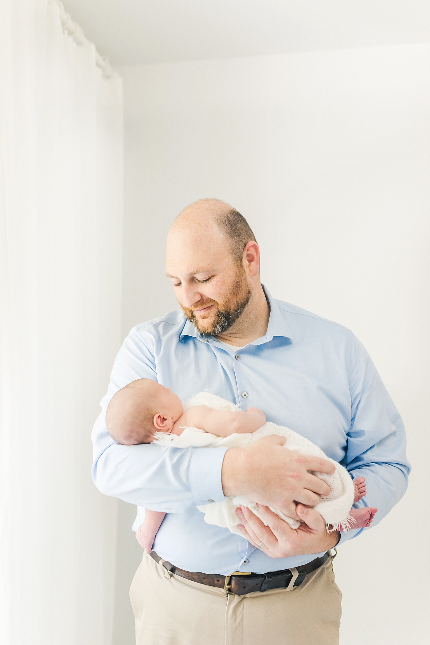 Dad in blue holding his newborn baby boy | Photo by Anna Wisjo Photography