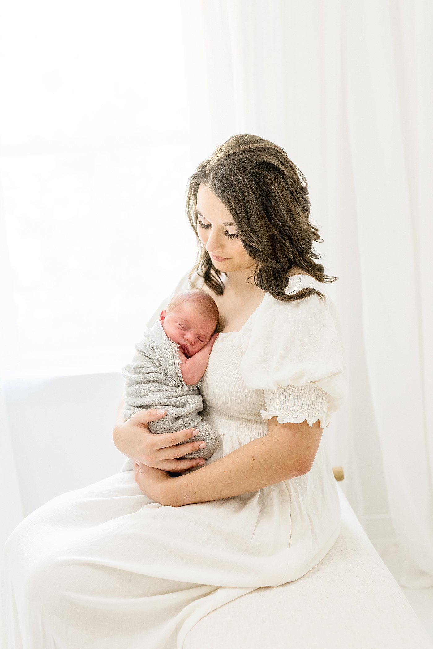 Mom in long white dress holding her newborn | Photo by North Carolina Newborn Photographer Anna Wisjo 