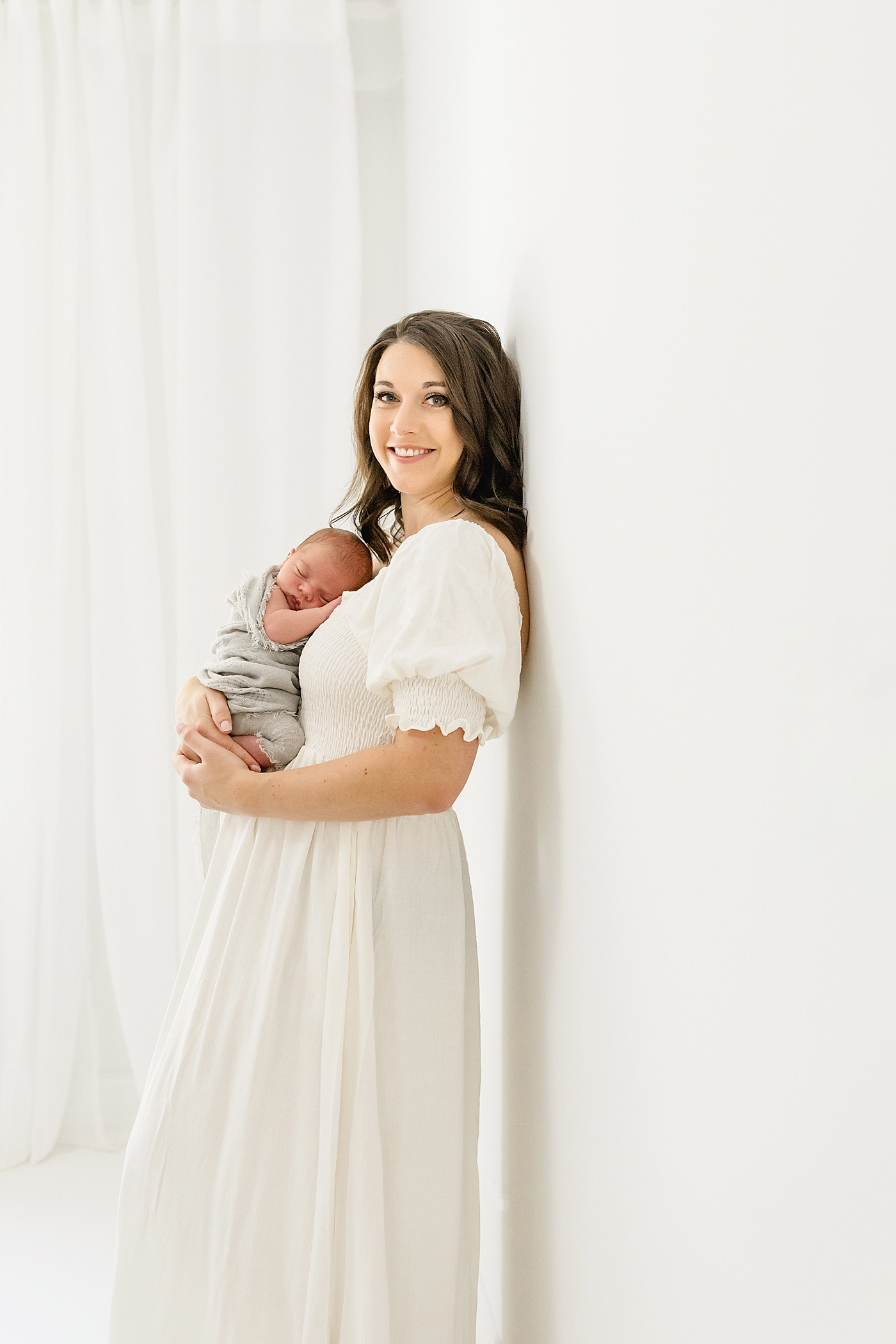 Mom in white dress holding her new baby | Photo by North Carolina Newborn Photographer Anna Wisjo 